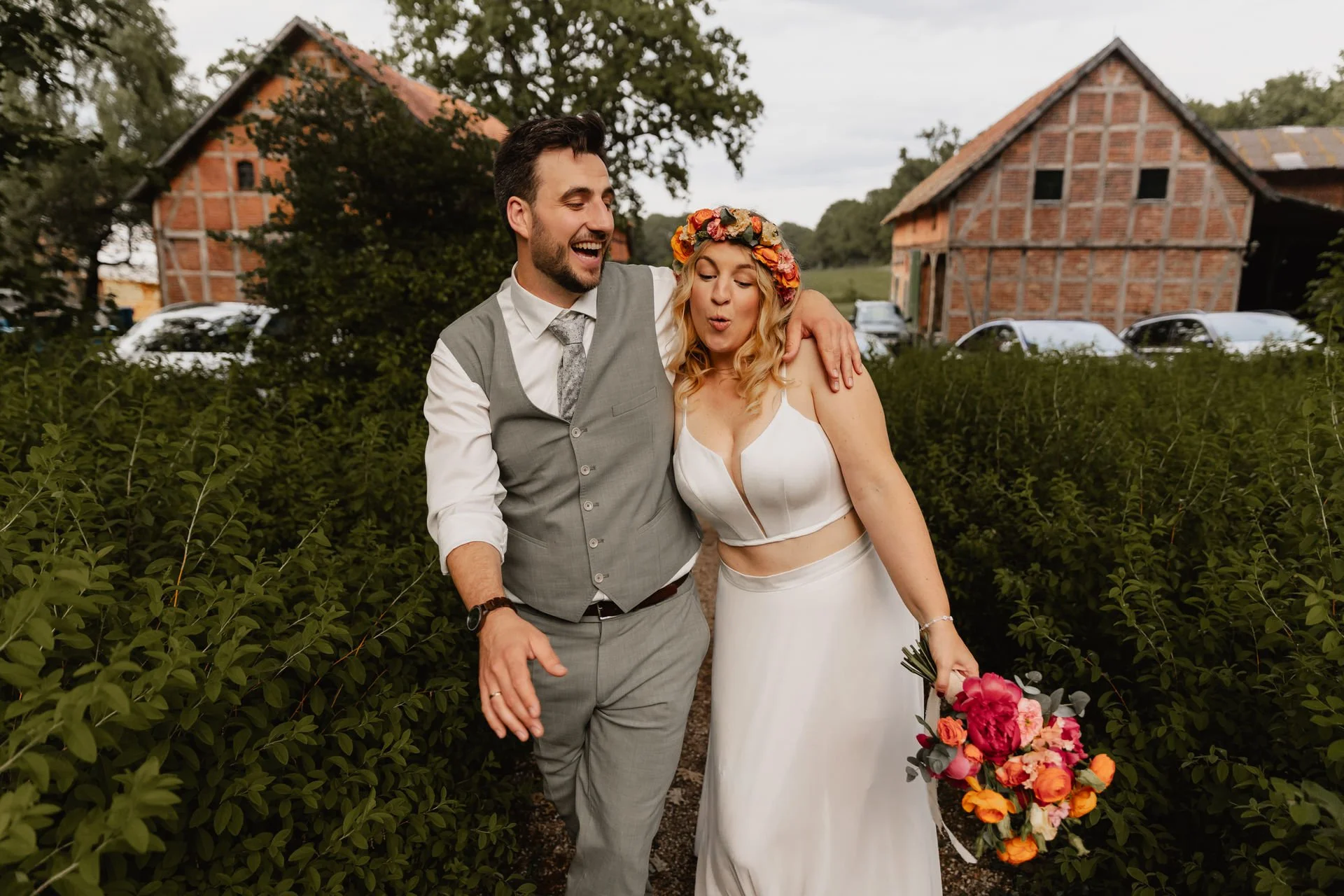 Lachendes Brautpaar vor einer rustikalen Scheune in Lüneburg an ihrem Hochzeitstag