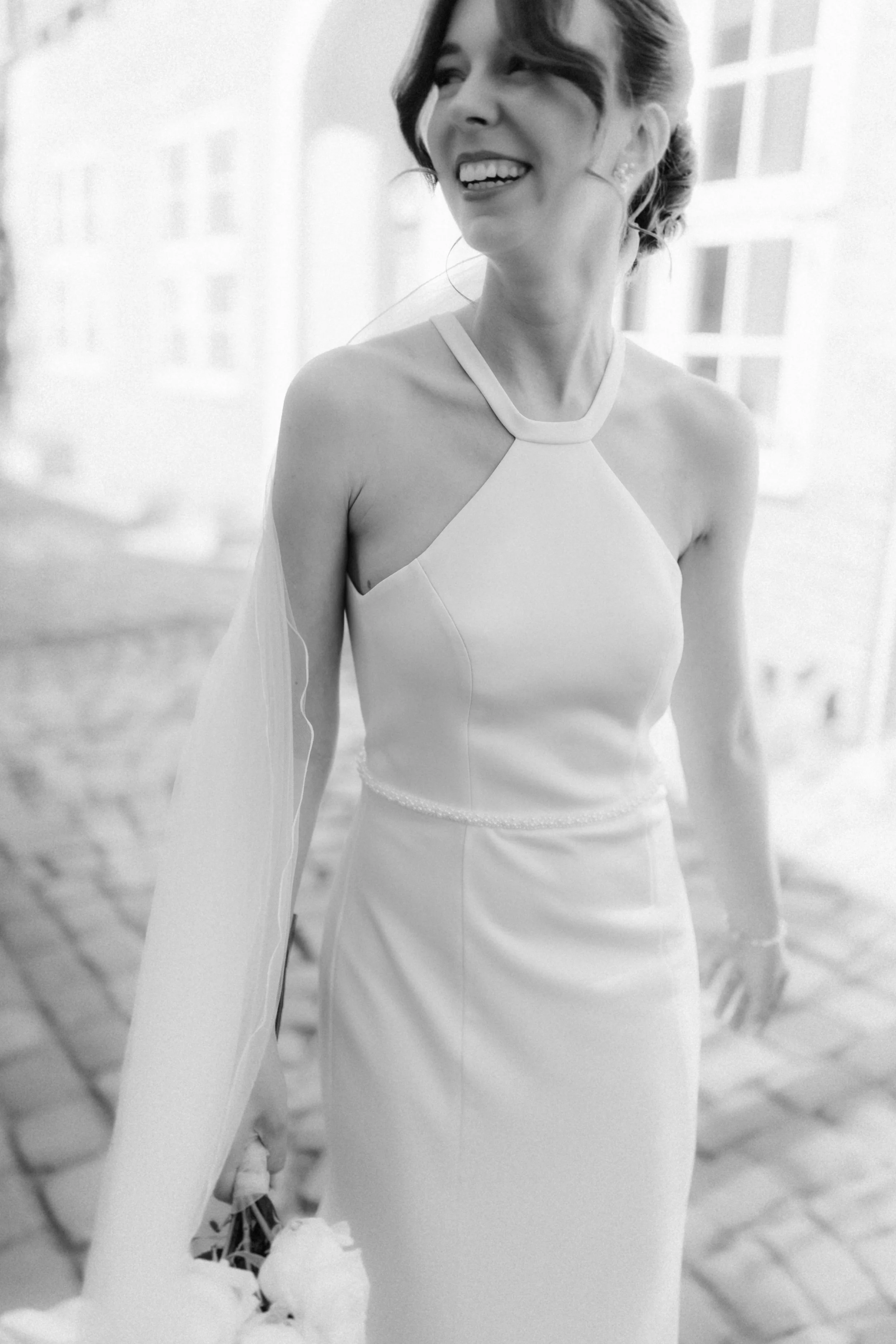 Lachende Braut im modernen Brautkleid als natürliche Schwarz-Weiß-Aufnahme in der Lüneburger Altstadt.