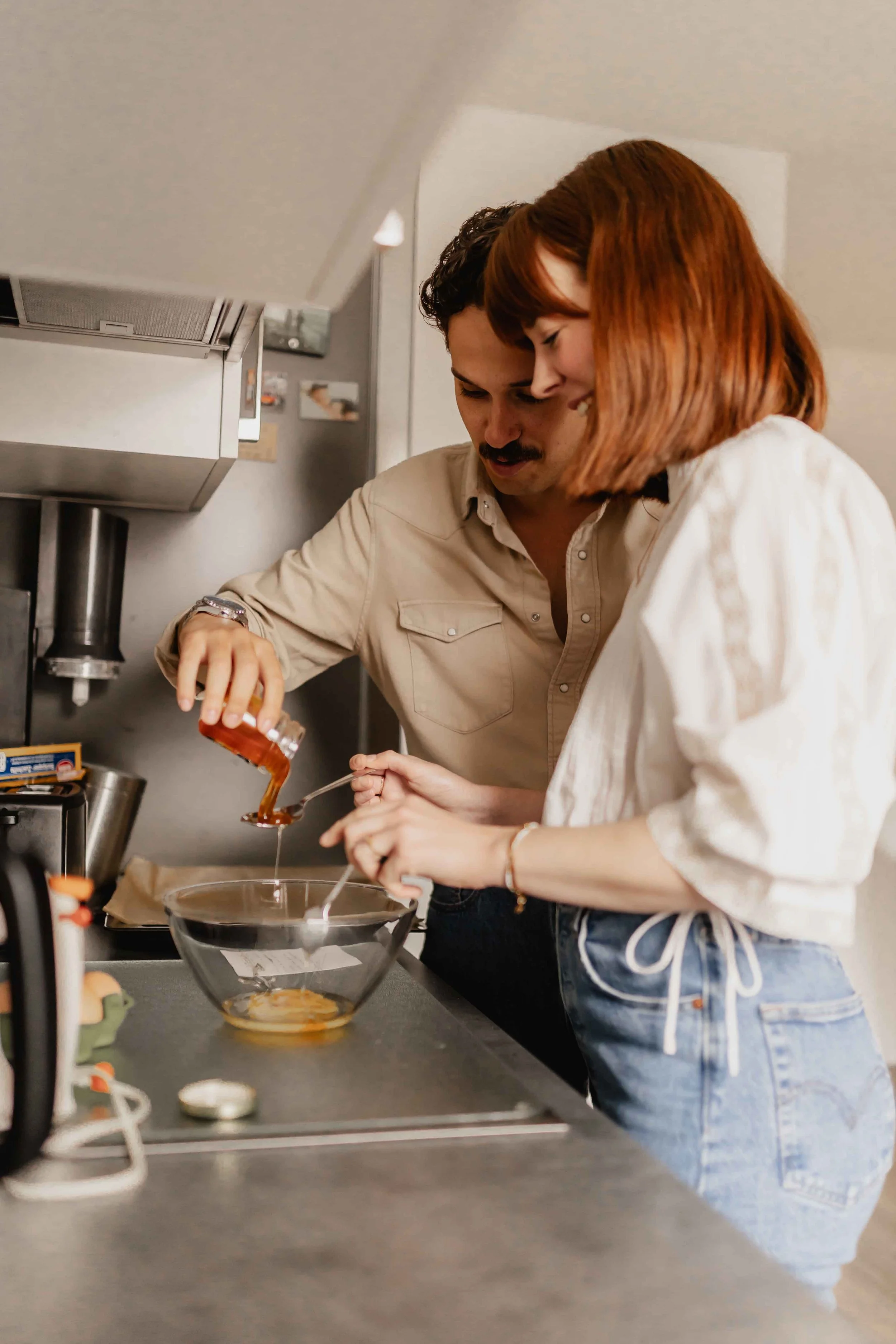 Paar kocht gemeinsam in der Küche, er steht nah hinter ihr und beide würzen das Essen bei einer Homestory in Lüneburg