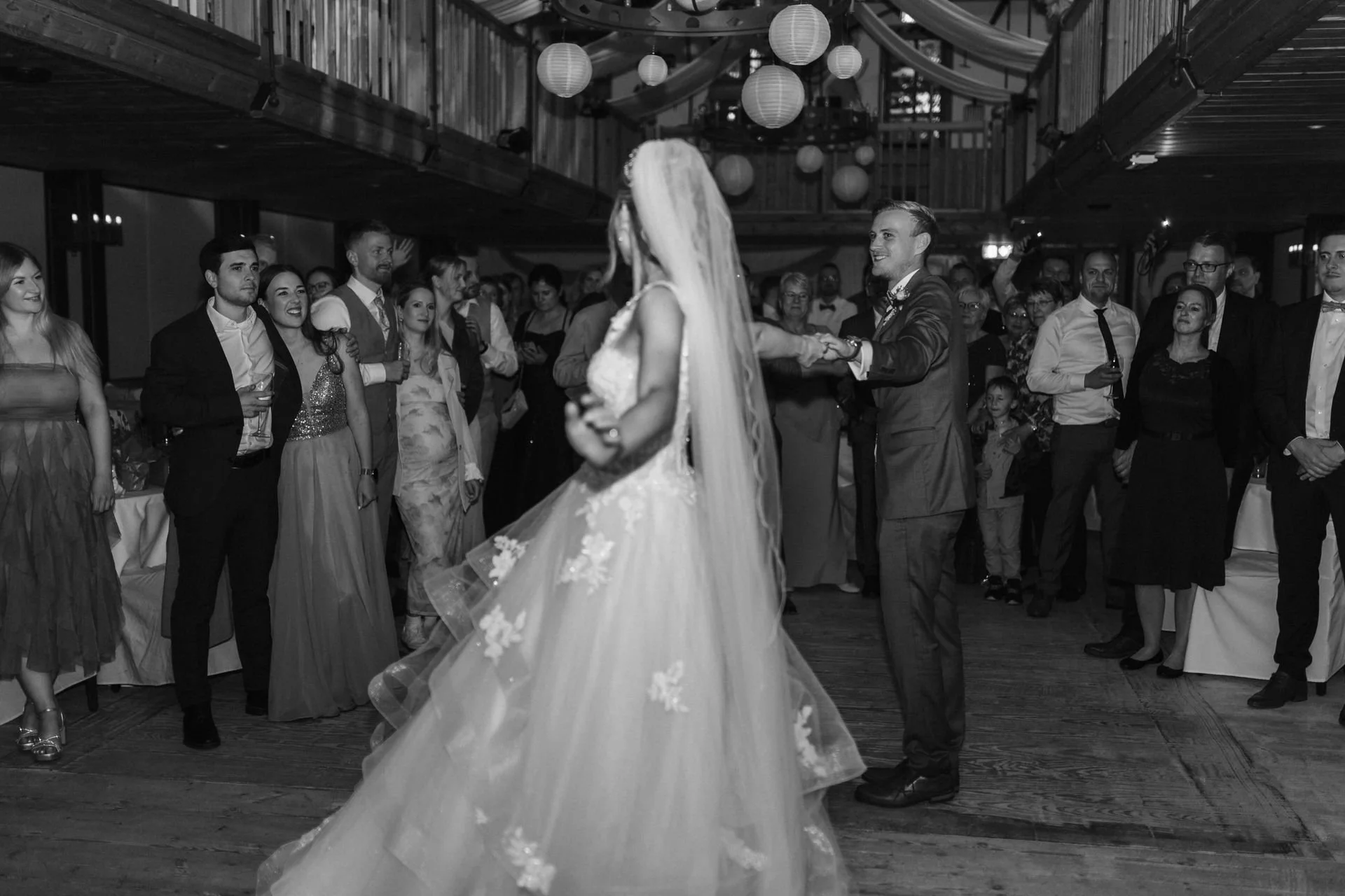 Braut und Bräutigam beim Hochzeitstanz, umgeben von ihren Gästen im festlich geschmückten Saal des Heide Hotels Reinstorf bei Lüneburg.