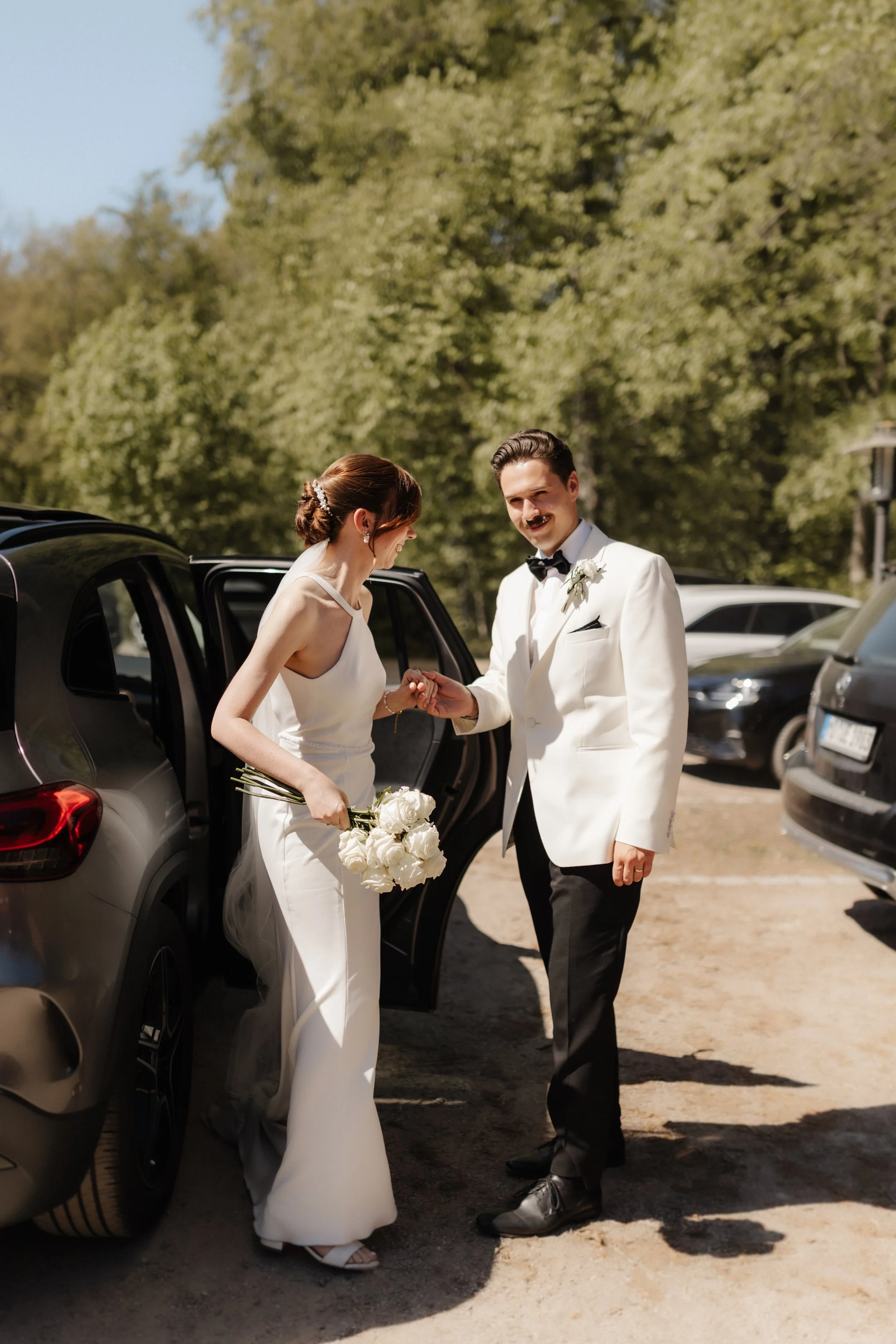 Bräutigam Niklas hilft seiner Braut Tina beim Aussteigen aus dem Auto und hält liebevoll ihre Hand. Ein natürlicher Moment am Hochzeitstag in Lüneburg.