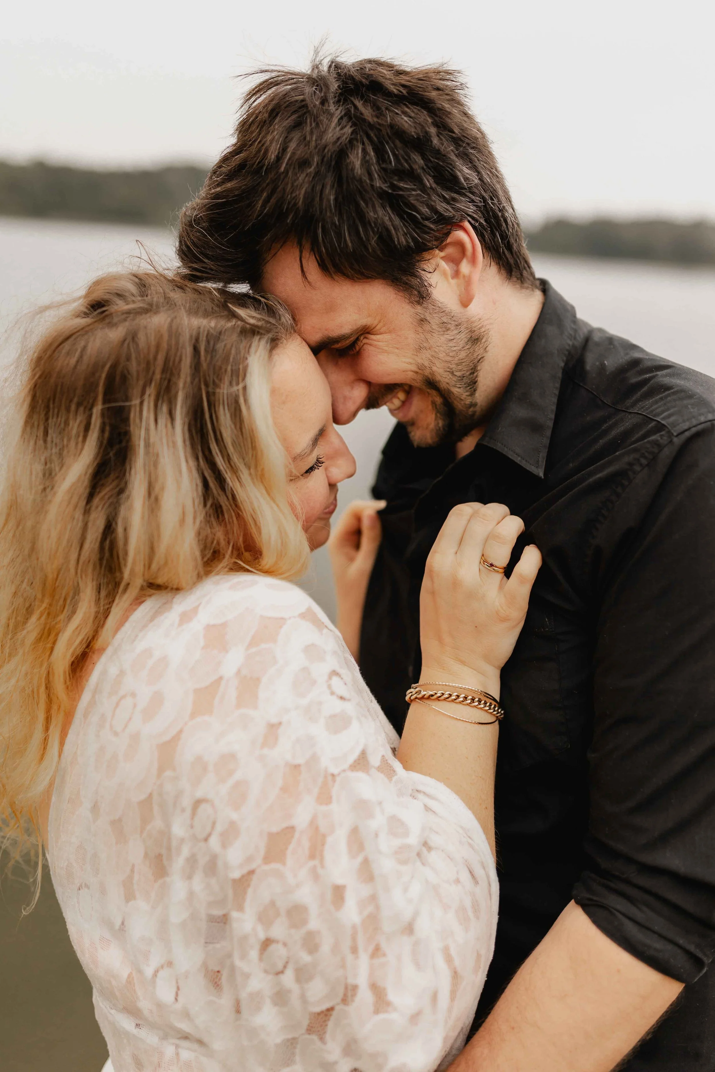 Paar steht eng umschlungen im Wasser und lächelt vertraut aneinandergelehnt