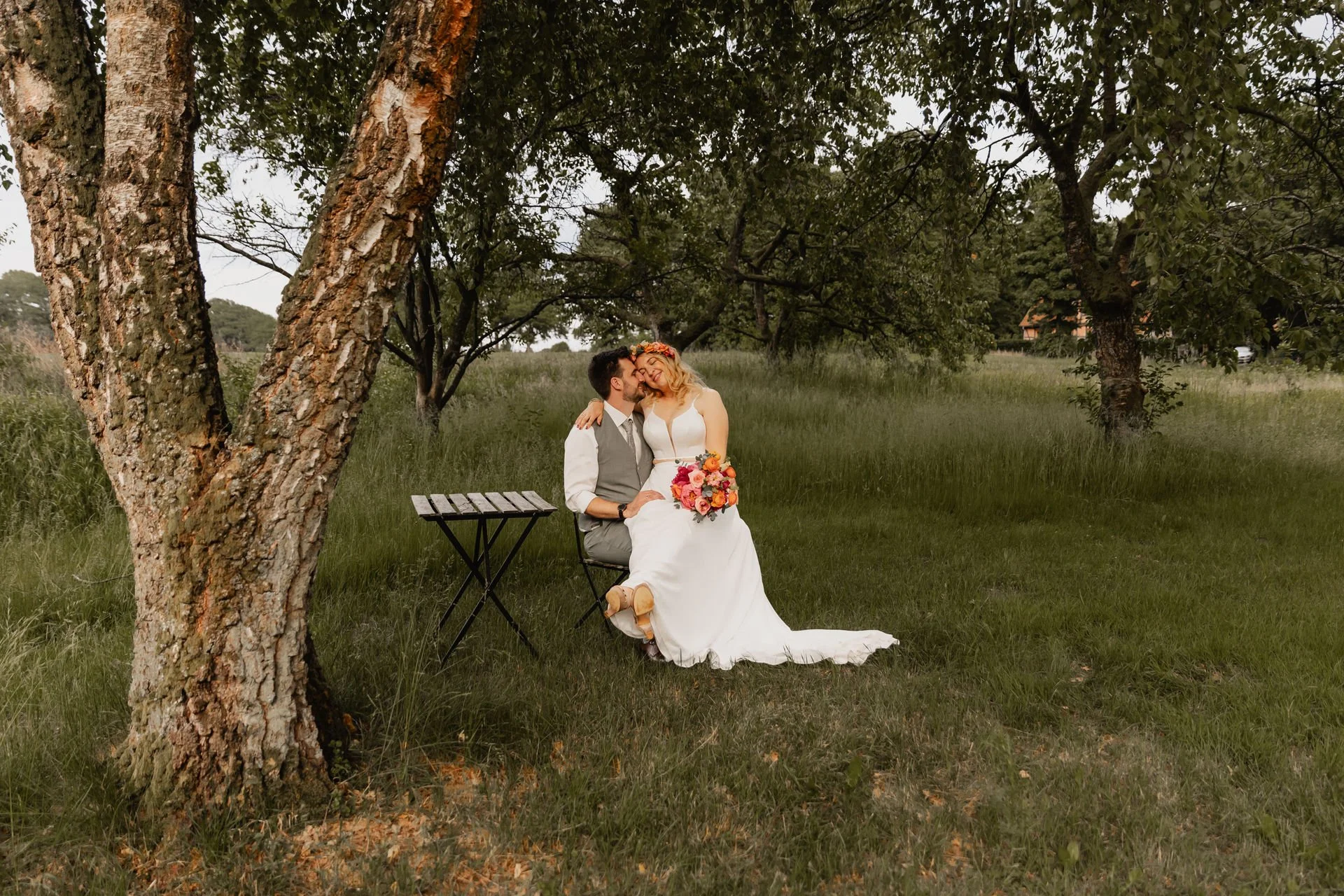 Brautpaar sitzt unter einem Baum und küsst sich bei ihrer Hochzeit in Lüneburg