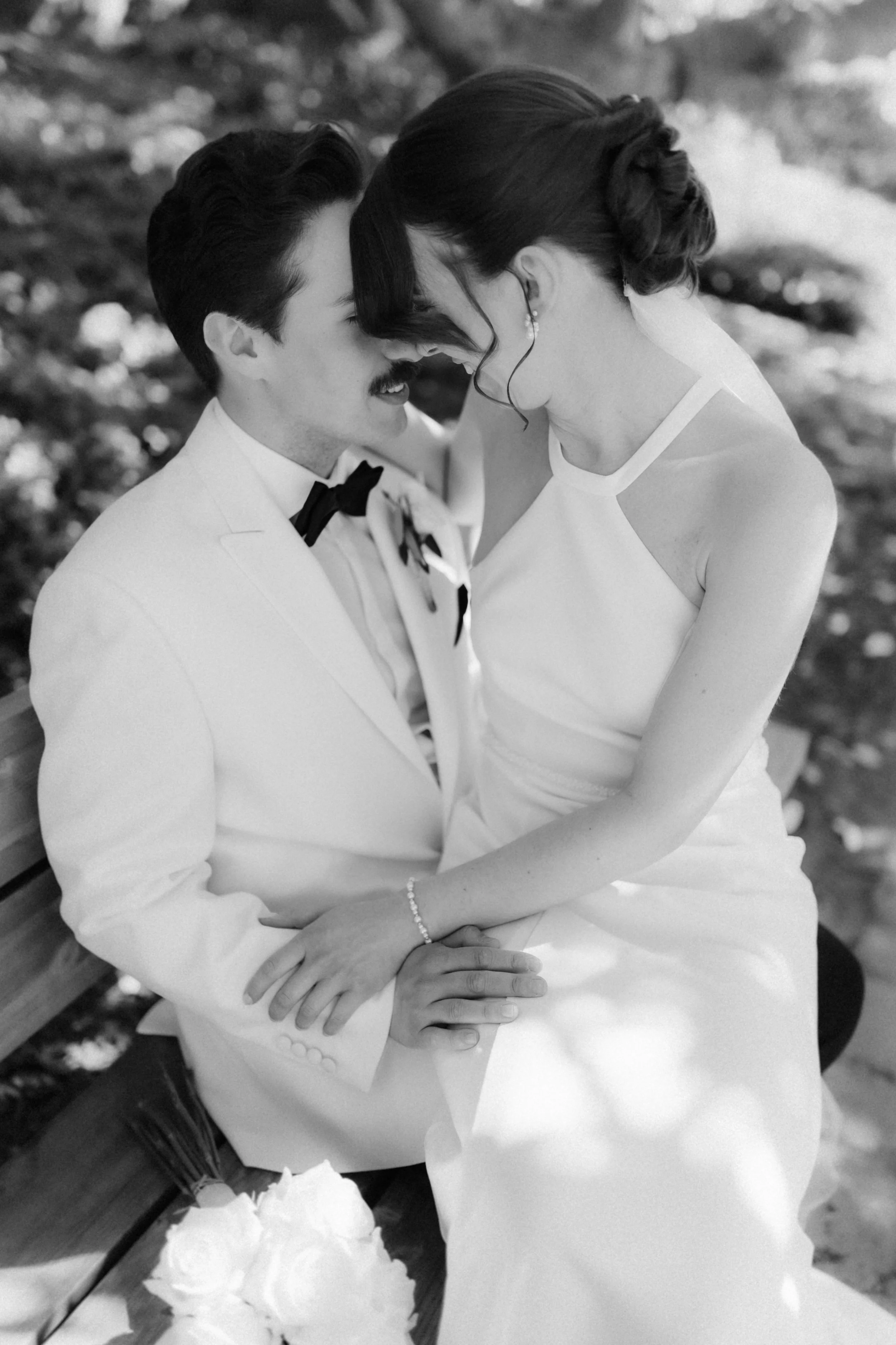 Inniges Schwarz-Weiß-Foto eines Brautpaares bei seiner Hochzeit in Lüneburg, das sich lächelnd aneinanderlehnt.