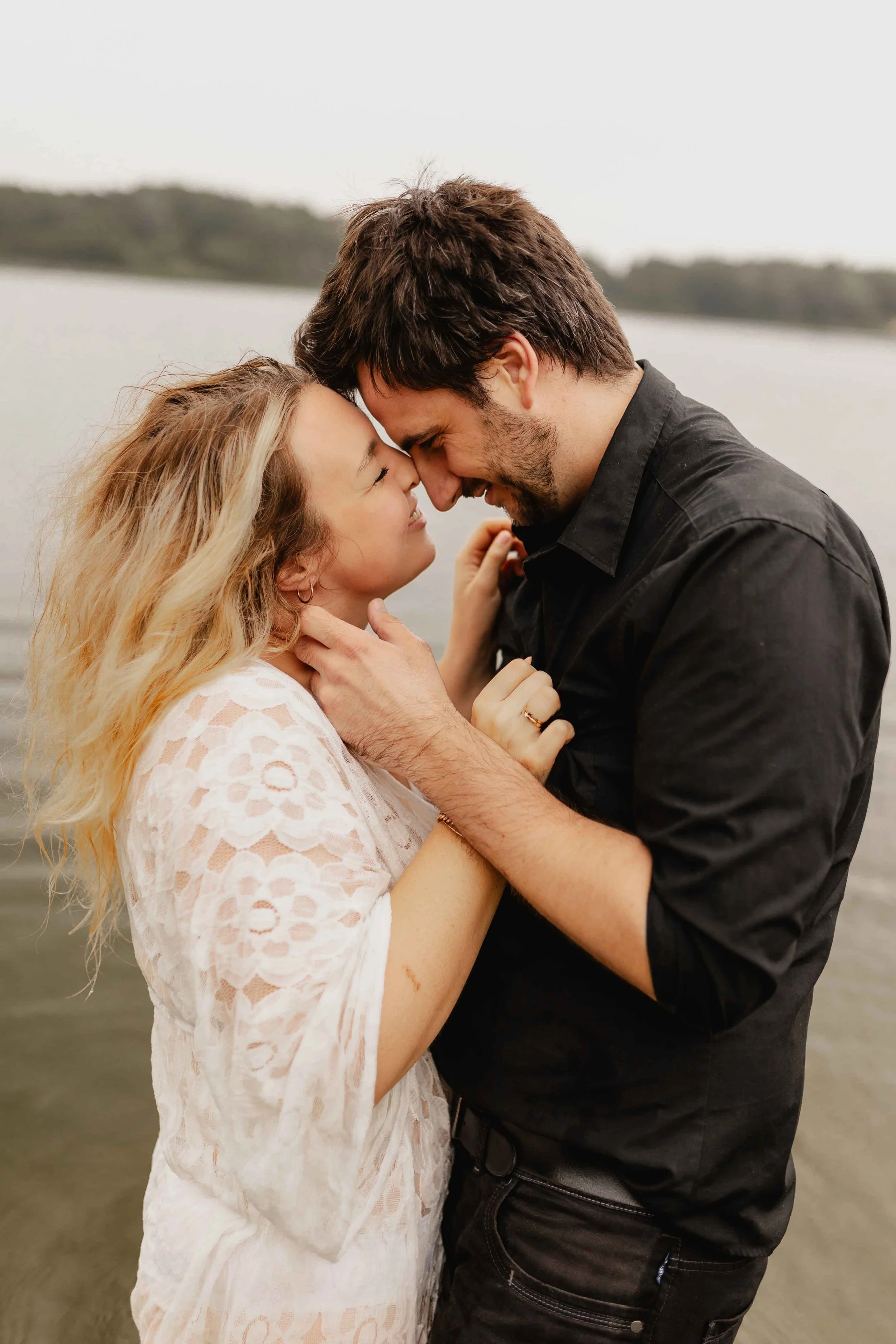 Paar im Wasser hält sich sanft im Gesicht und berührt sich Stirn an Stirn kurz vor einem Kuss