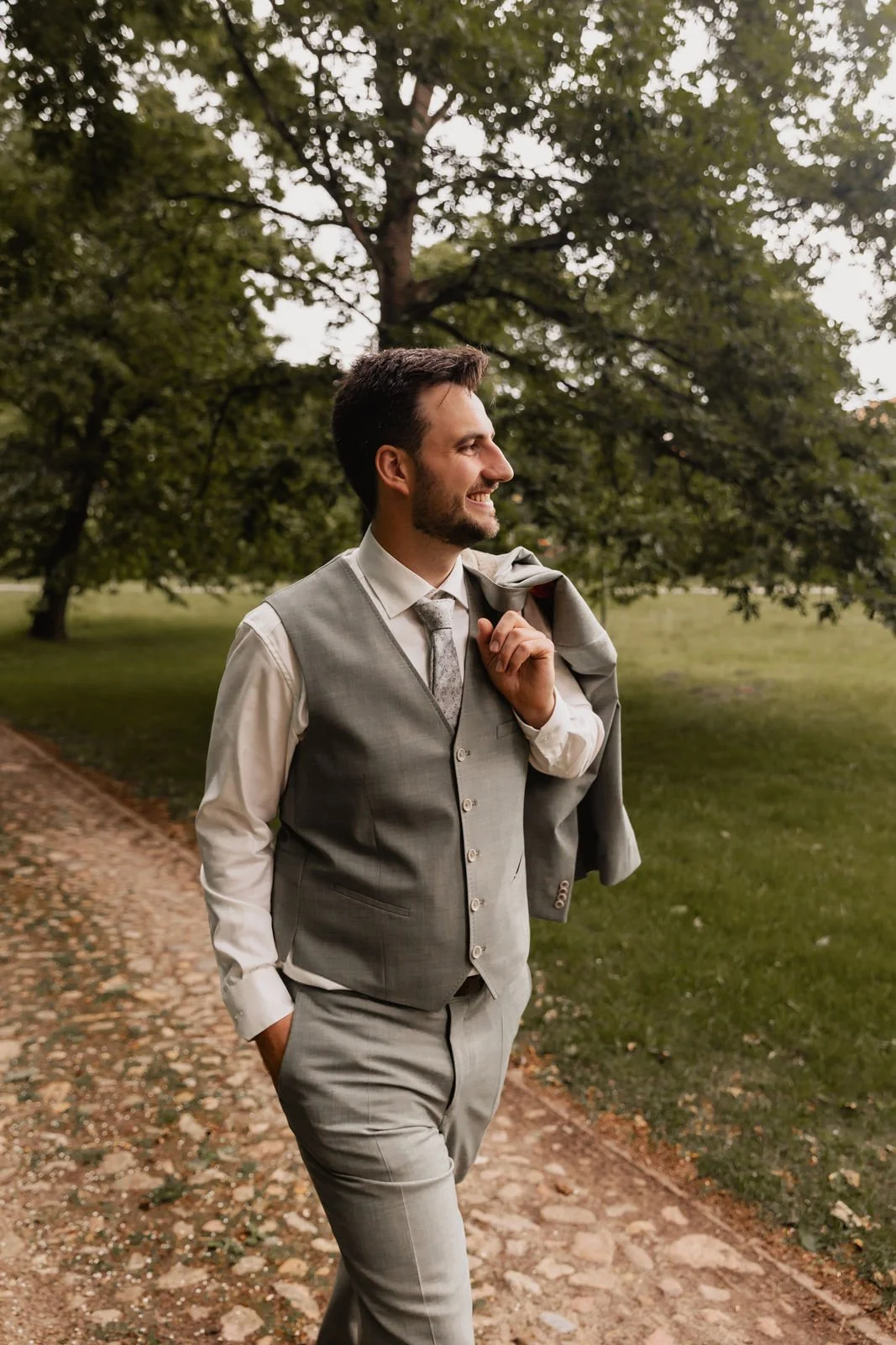 Bräutigam spaziert in Weste und Hemd auf einem Weg im Grünen bei seiner Hochzeit in Lüneburg