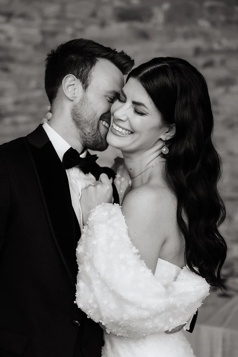 Inniger Moment eines lachenden Brautpaares bei einem eleganten Hochzeitsportrait in Schwarz-Weiß