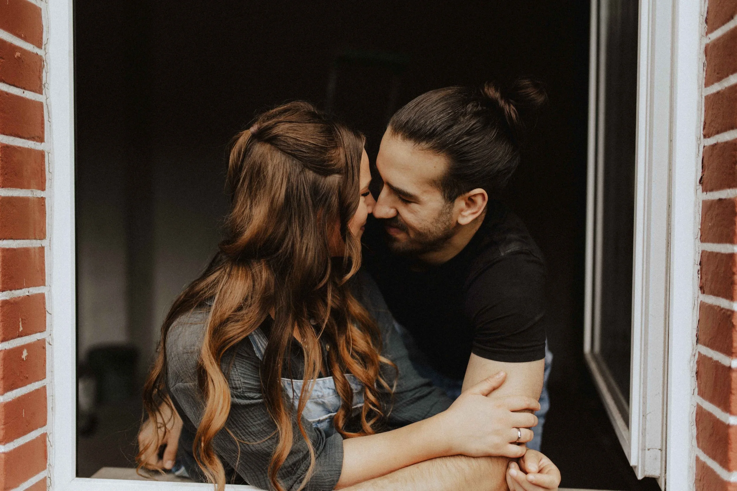 Baustellenshooting mit einem Paar in der Nähe von Uelzen bei Lüneburg. Beide sind im Fensterrahmen und sind eng aneinander geschlungen und sehen sich dabei an.