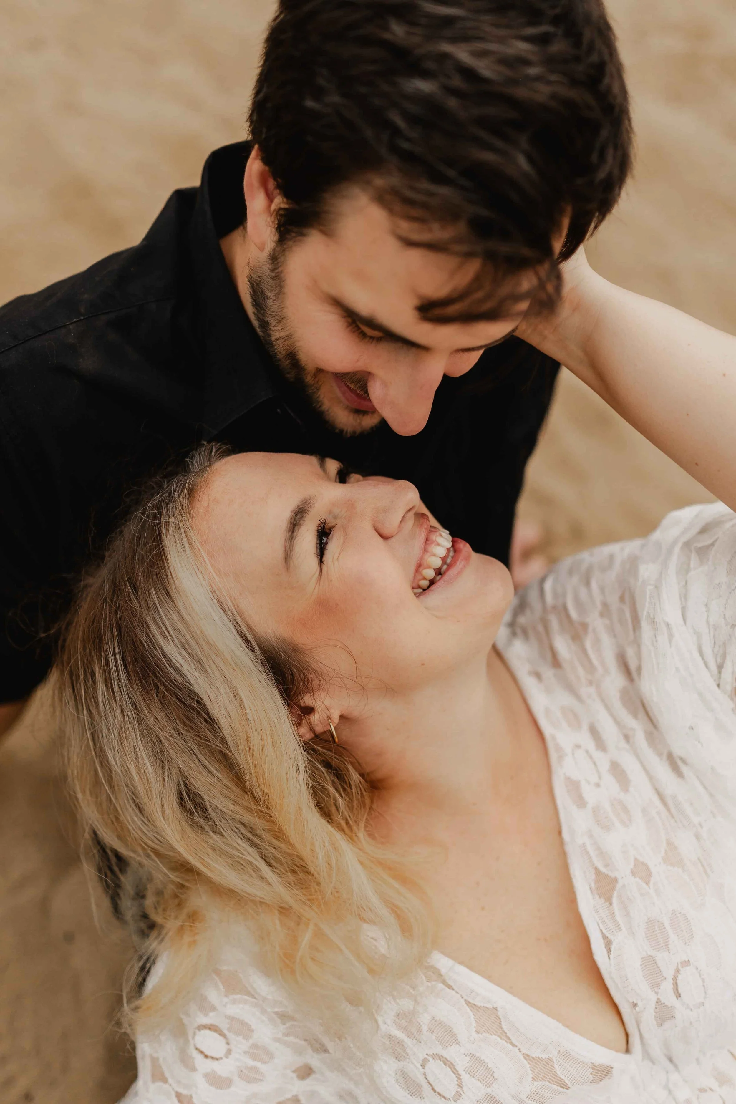 Paar liegt eng beieinander und schaut sich mit einem verliebten Lächeln in die Augen