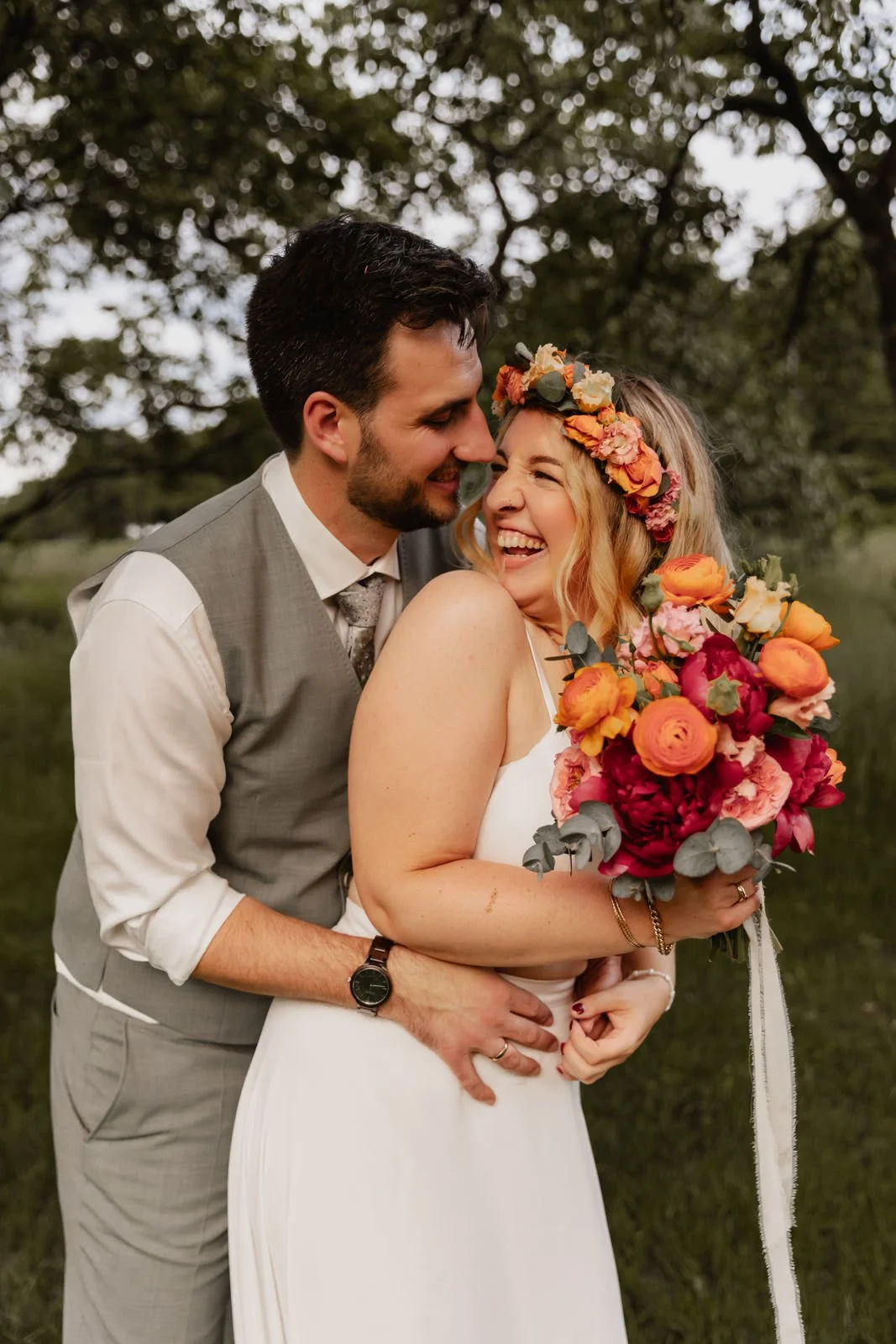 Braut mit farbenfrohem Blumenstrauß wird liebevoll vom Bräutigam umarmt bei ihrer Hochzeit in Lüneburg