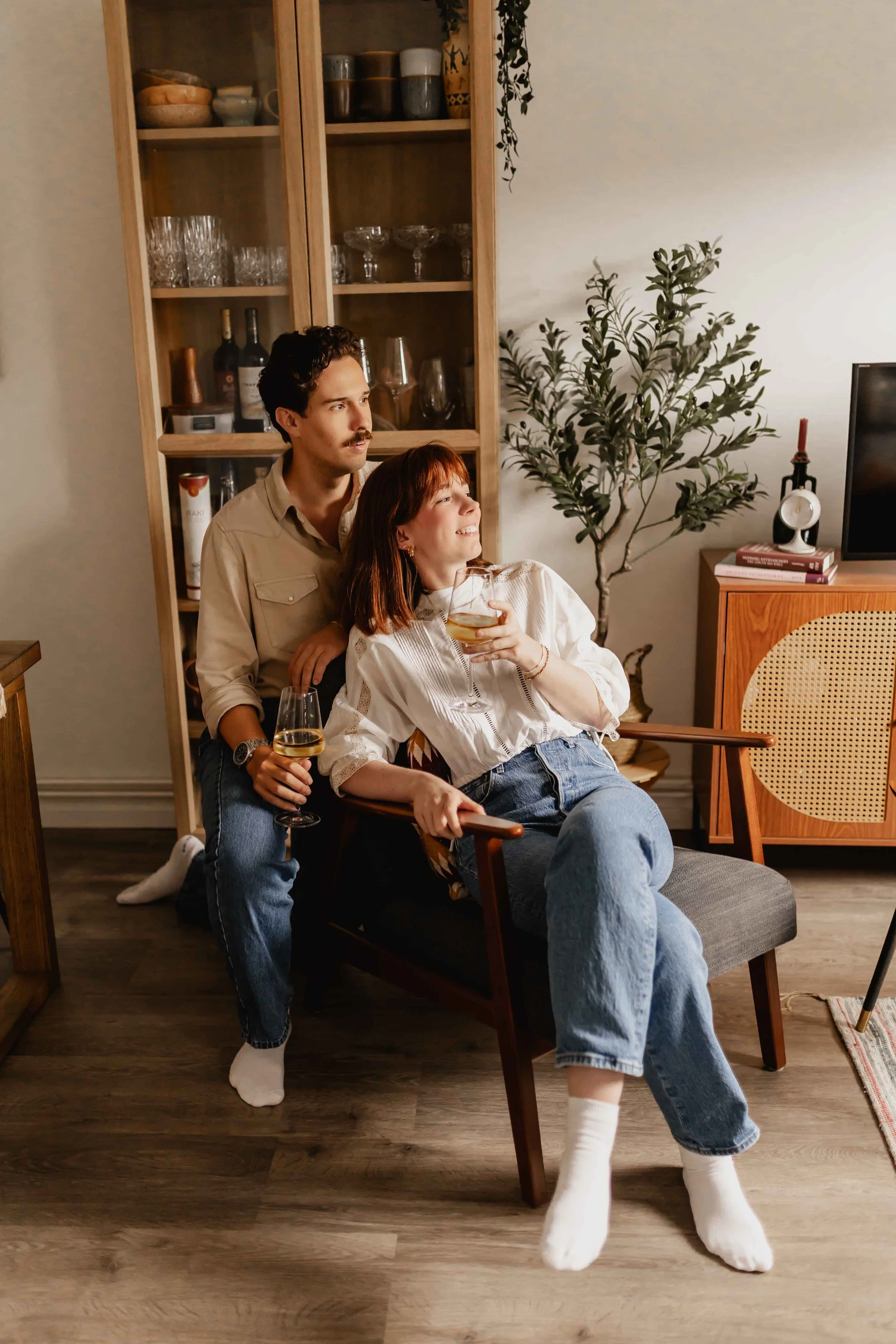 Paar bei einer Homestory in Lüneburg sitzt entspannt zusammen mit Weingläsern und schaut aus Fenster