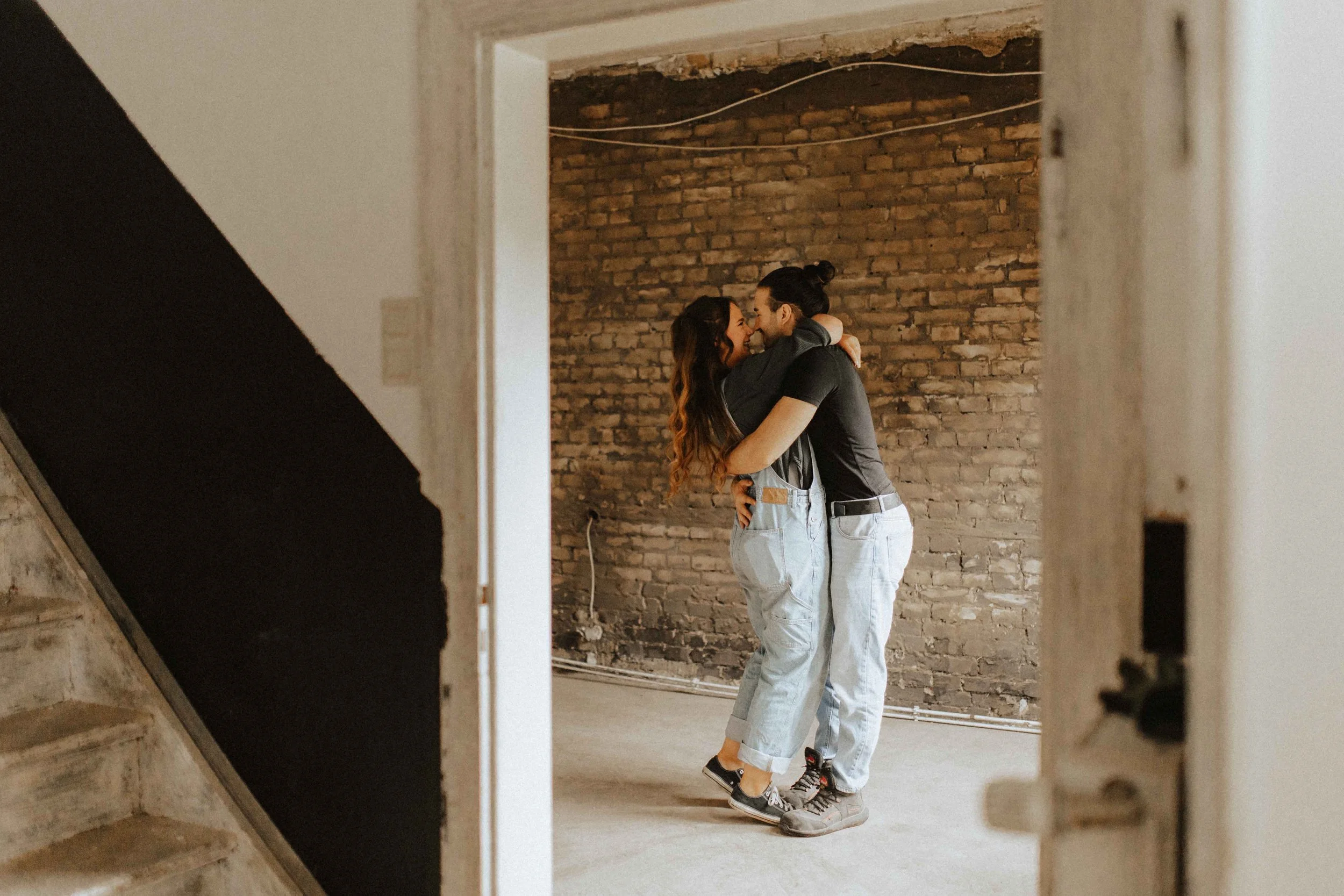 Paarshooting auf Baustelle – innige Umarmung und Kuss vor einer Backsteinwand in Lüneburg.