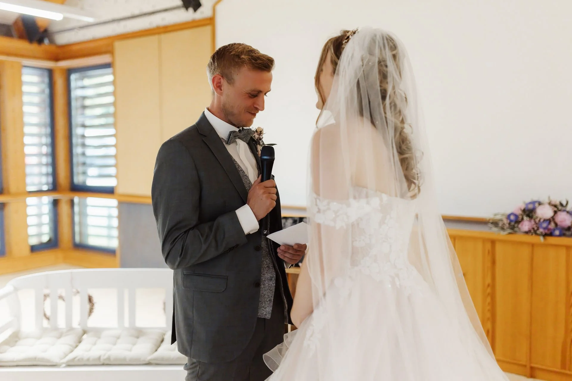 Emotionaler Moment während der freien Trauung im Heide Hotel Reinstorf bei Lüneburg: Der Bräutigam liest mit Mikrofon sein persönliches Eheversprechen vor, während die Braut im weißen Hochzeitskleid vor ihm steht.
