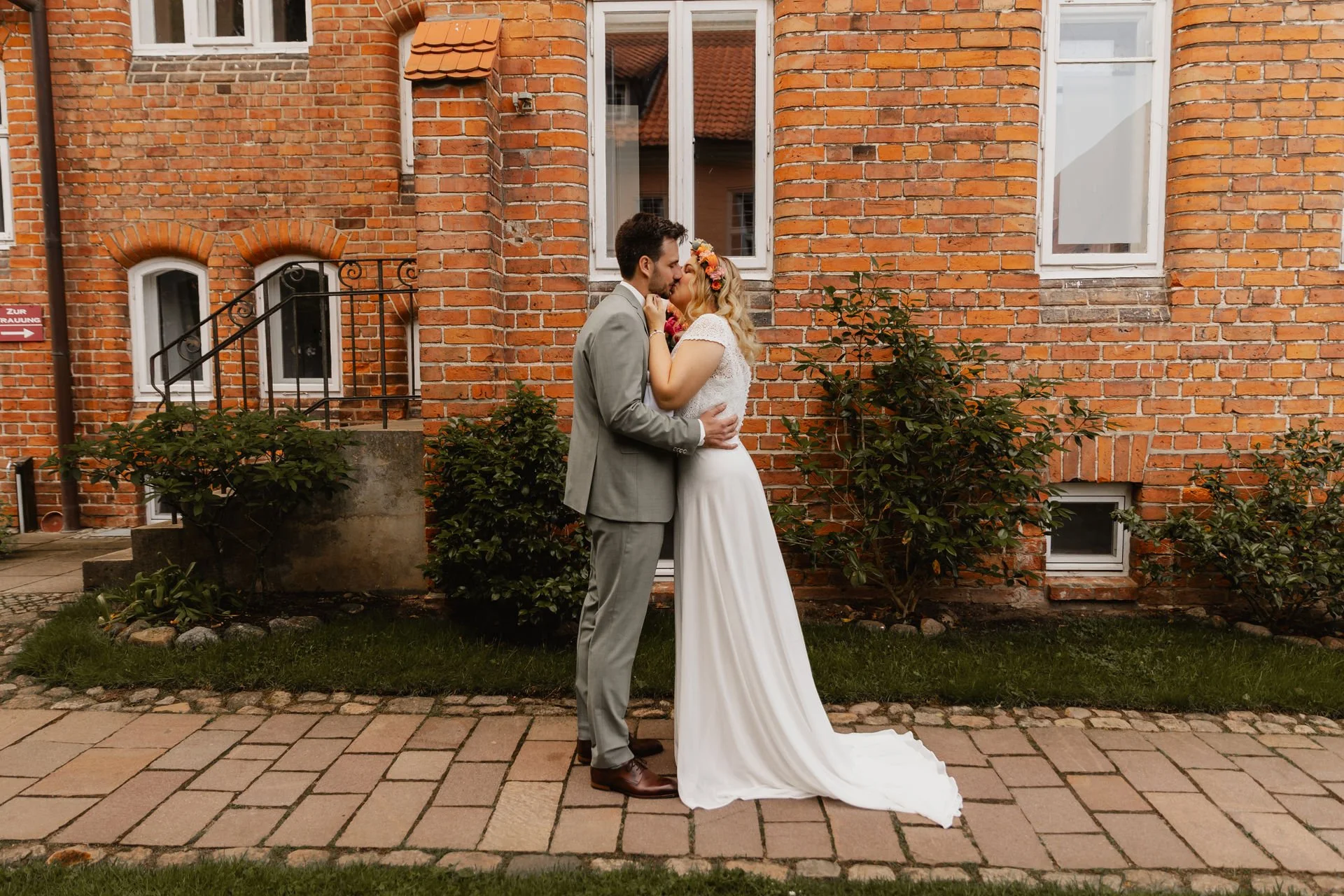 Brautpaar küsst sich vor einer roten Backsteinwand während ihrer Hochzeit in Lüneburg
