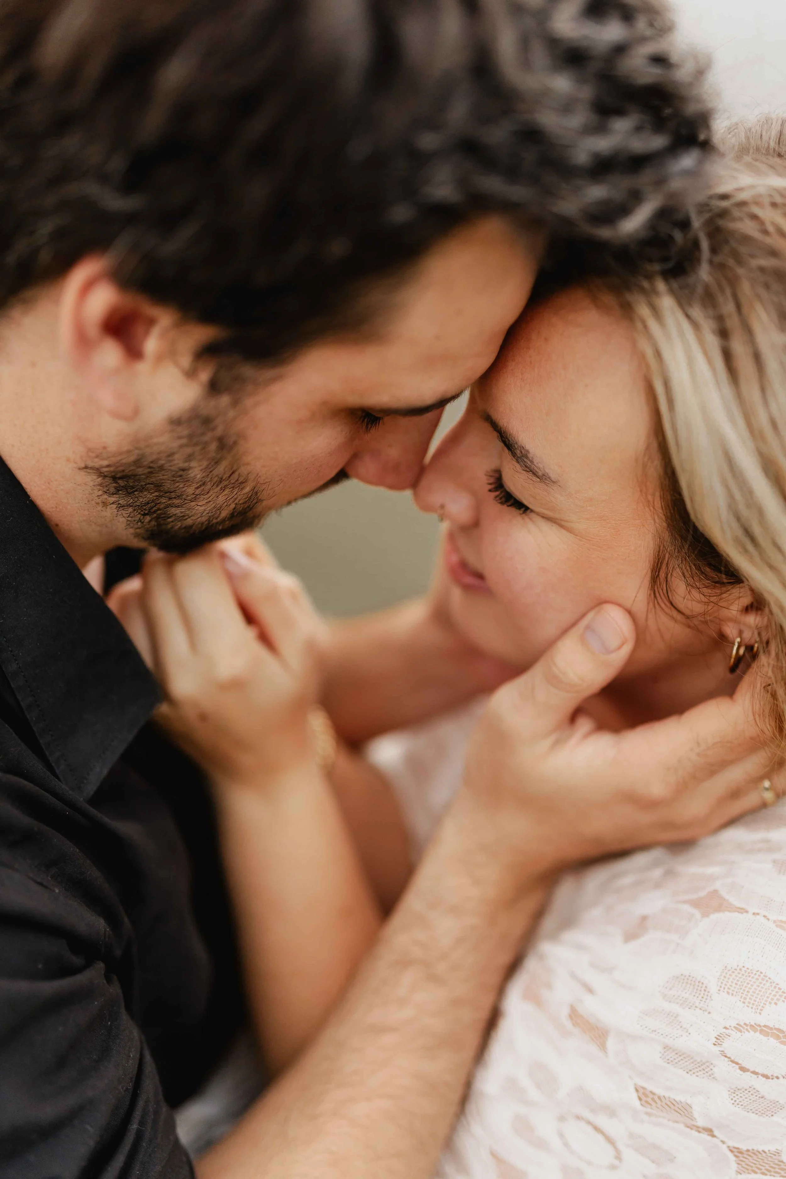 Paar hält sich zärtlich im Gesicht und schaut sich Stirn an Stirn mit einem Lächeln an