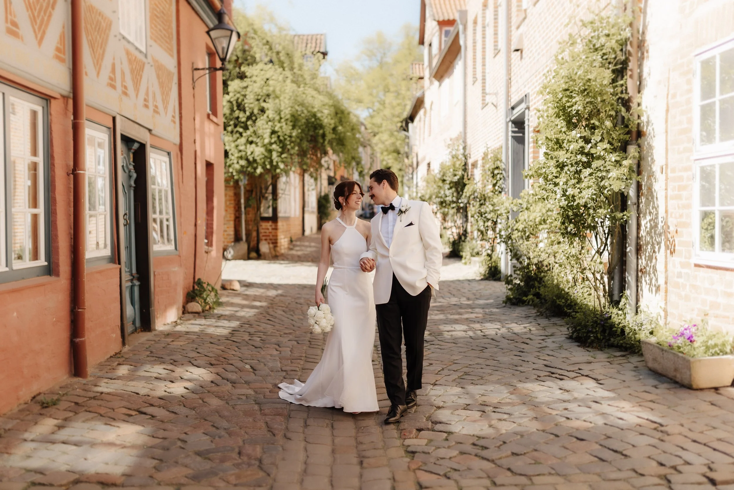 Brautpaar spaziert bei seiner Hochzeit gemeinsam durch eine historische Kopfsteinpflastergasse in der Lüneburger Altstadt.