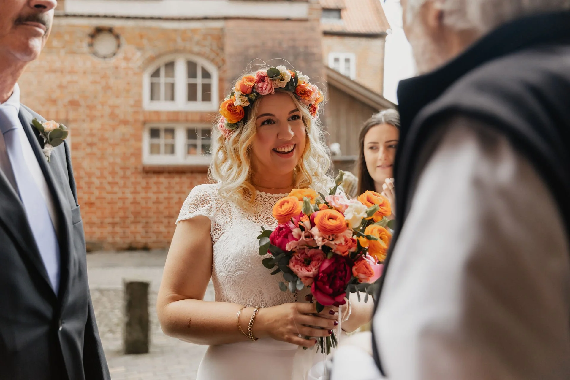 Lächelnde Braut mit Blumenkranz und Brautstrauß vor der Trauung in Lüneburg
