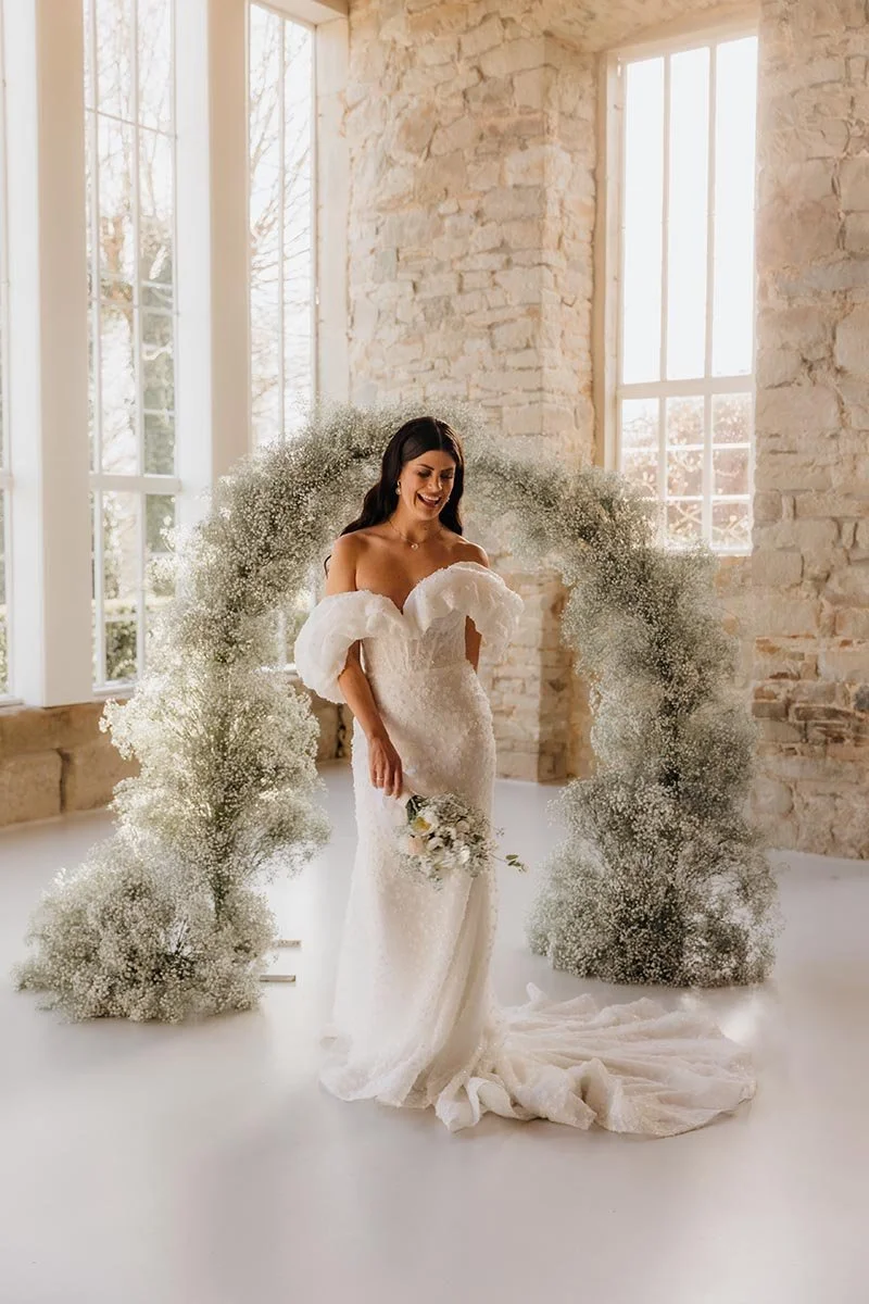 Elegante Braut bei einer Hochzeit in Lüneburg – modernes Brautkleid vor floralem Bogen in heller Hochzeitslocation