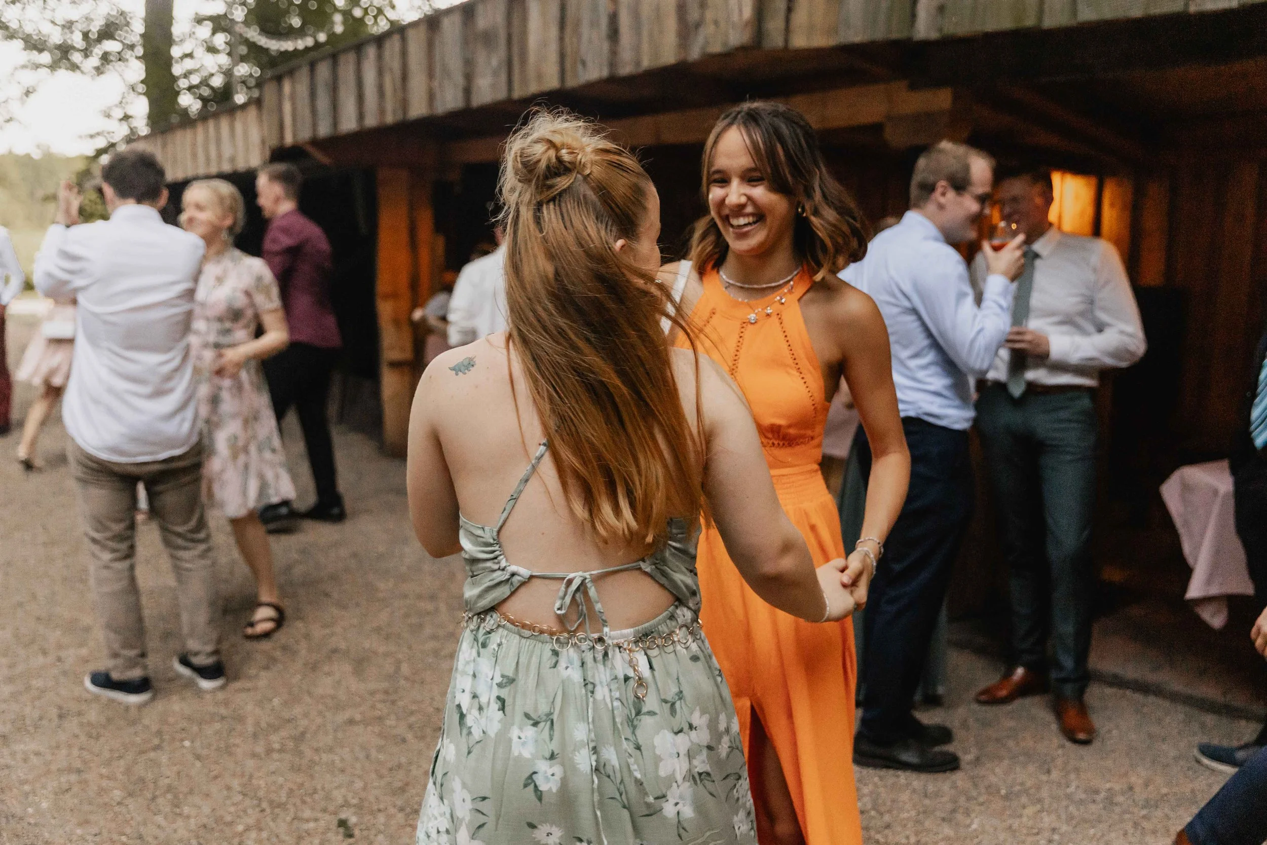 Zwei Freundinnen tanzen und lachen bei der Hochzeitsfeier im Innenhof