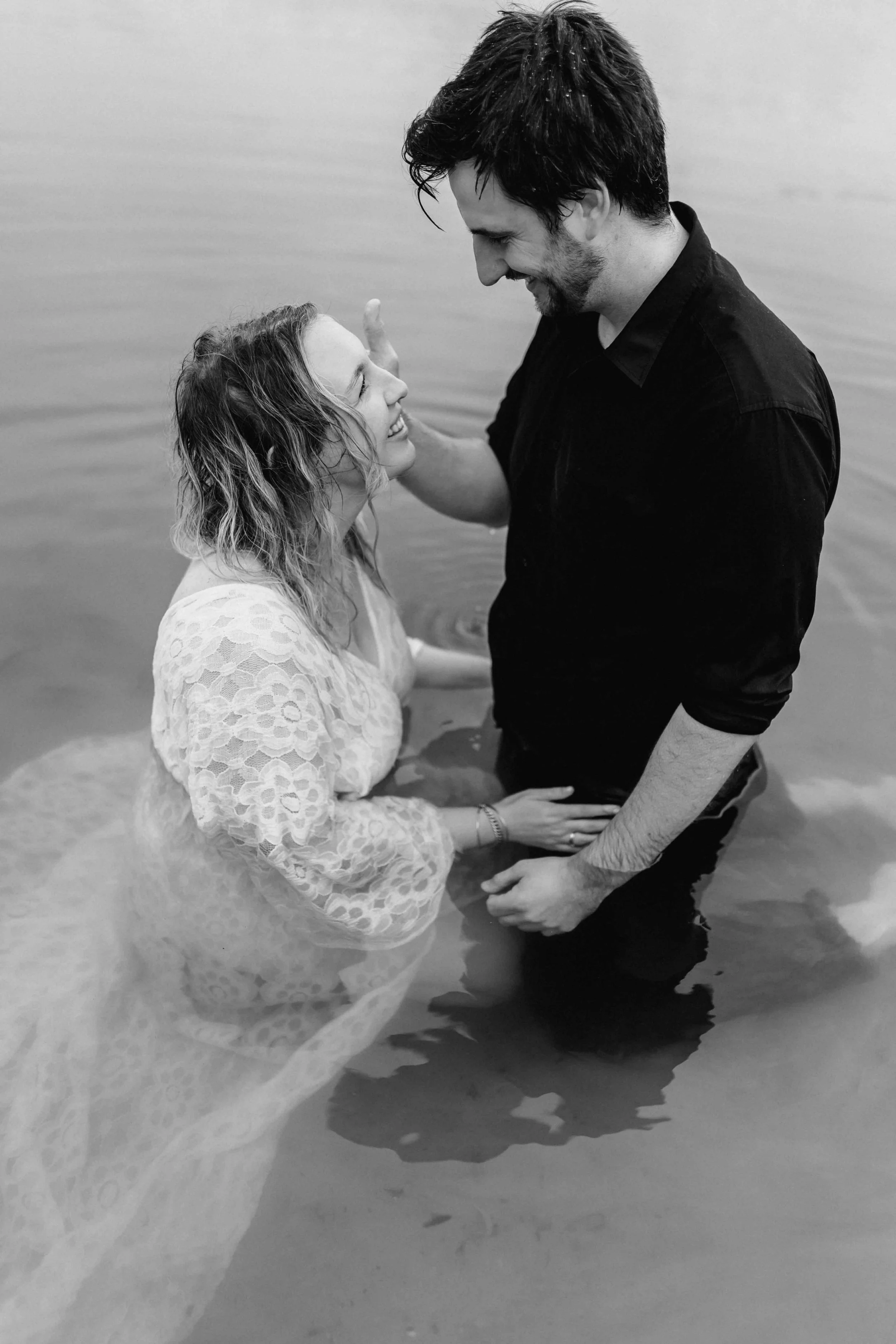 Paar im Wasser, er berührt zärtlich ihr Gesicht während sie sich tief in die Augen sehen