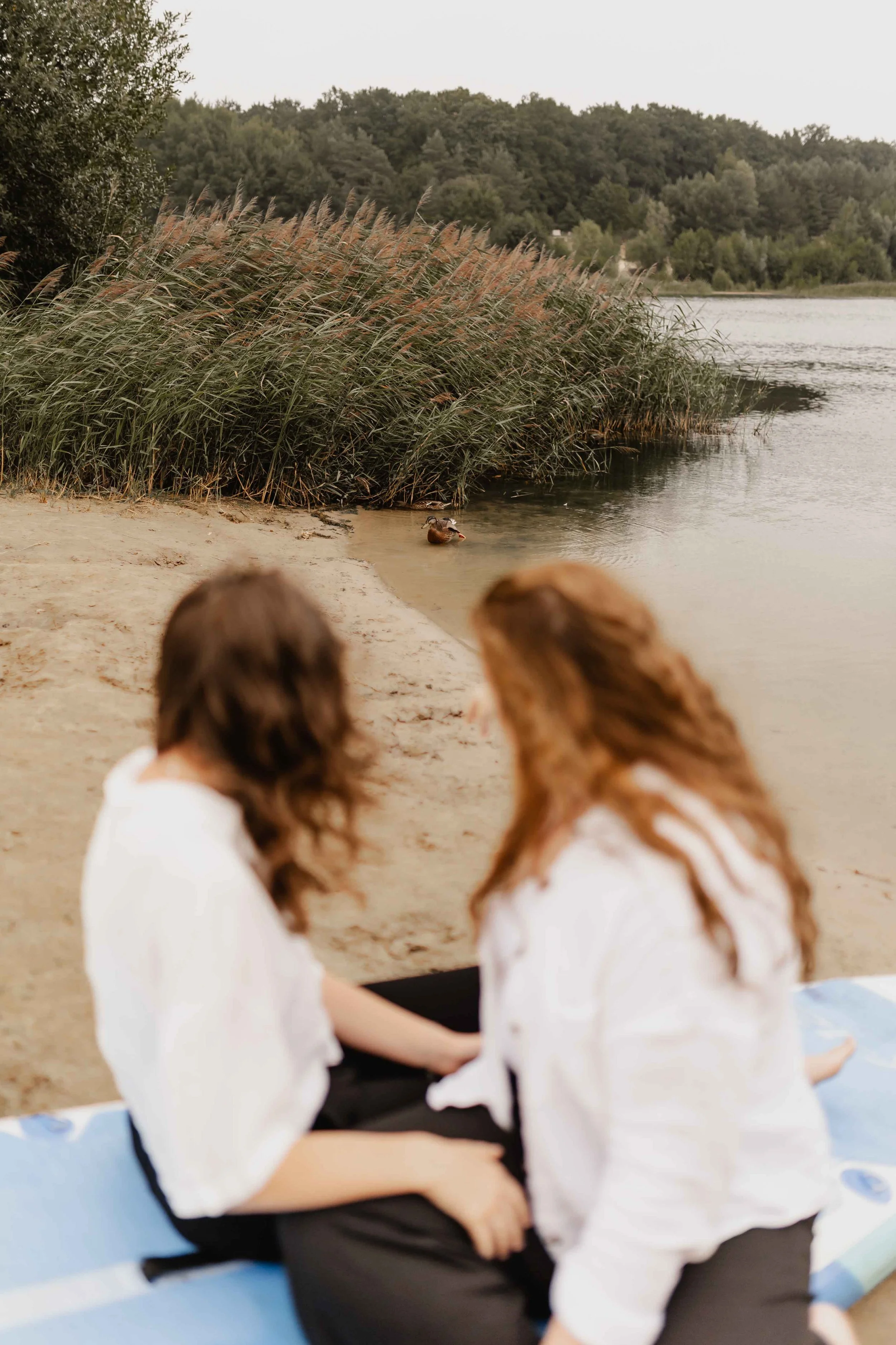Zwei Frauen sitzen auf einem SUP-Board am Oldenstädter See und blicken gemeinsam aufs Wasser
