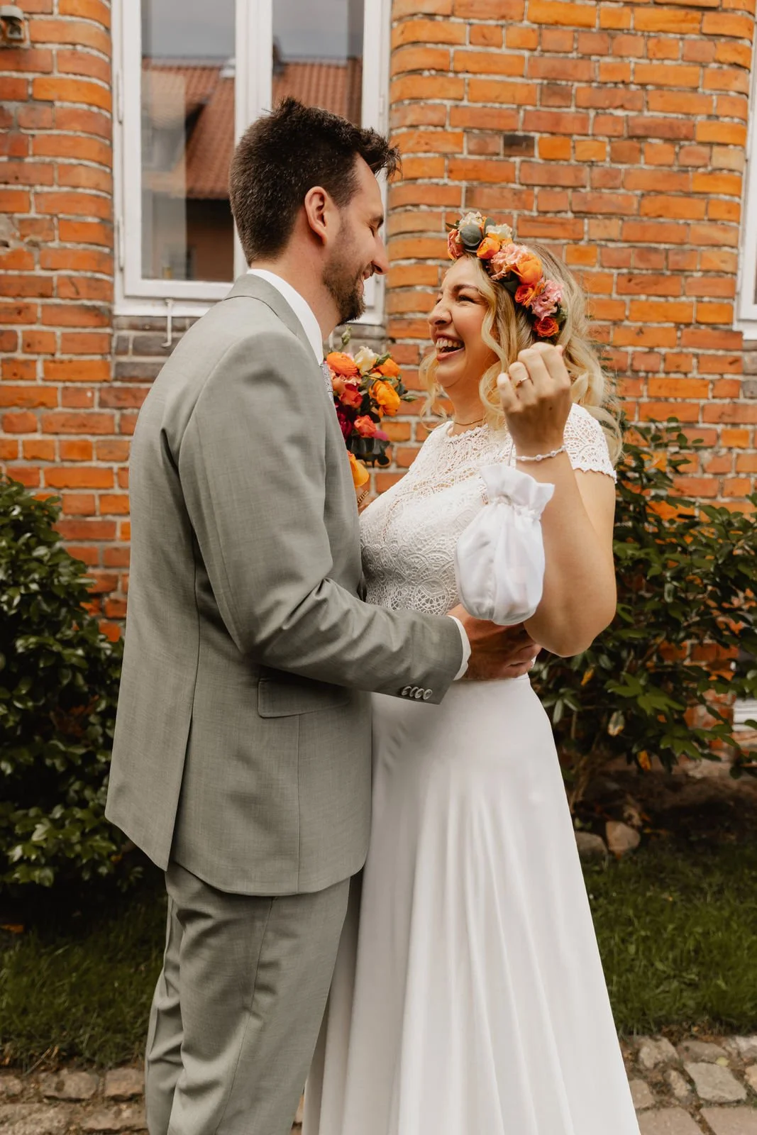 Lachendes Brautpaar vor einer roten Backsteinfassade bei ihrer Hochzeit in Lüneburg