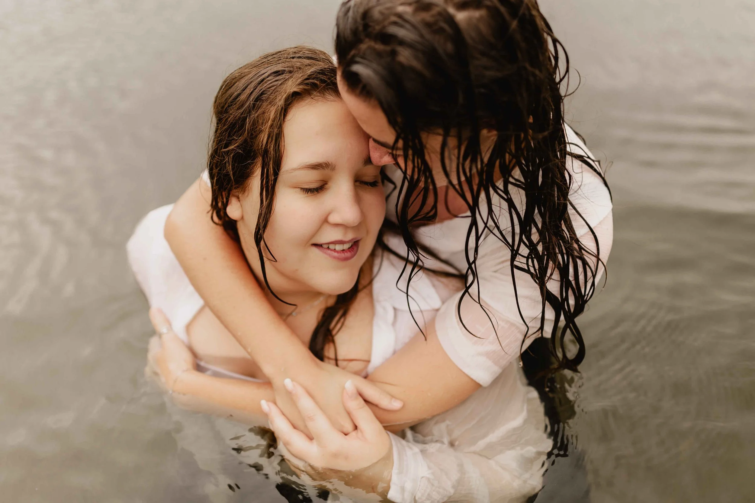 Zwei Frauen umarmen sich zärtlich im Wasser des Sees und genießen die Nähe