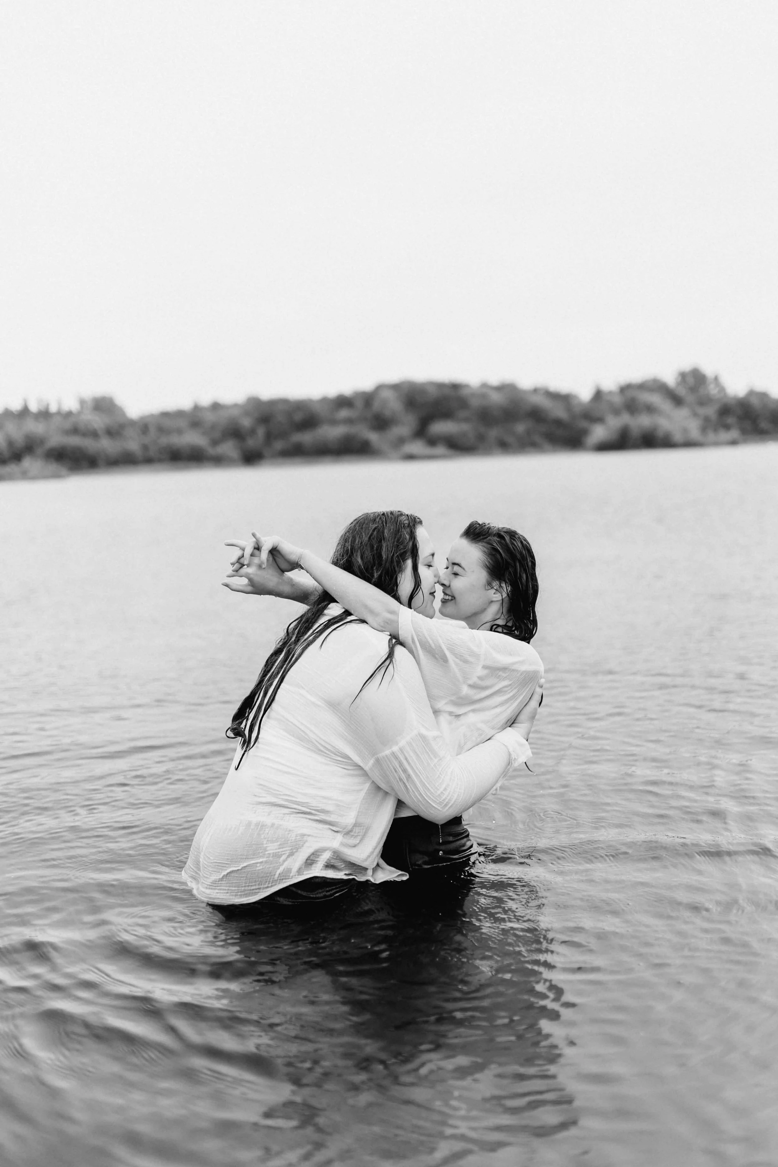 Zwei Frauen küssen sich innig im Wasser, romantisches Paarshooting in Schwarz-Weiß