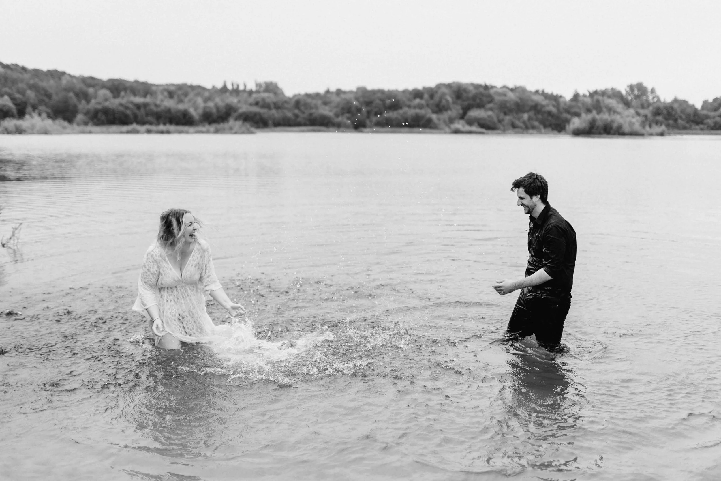 Paar lacht beim spielerischen Spritzen im See