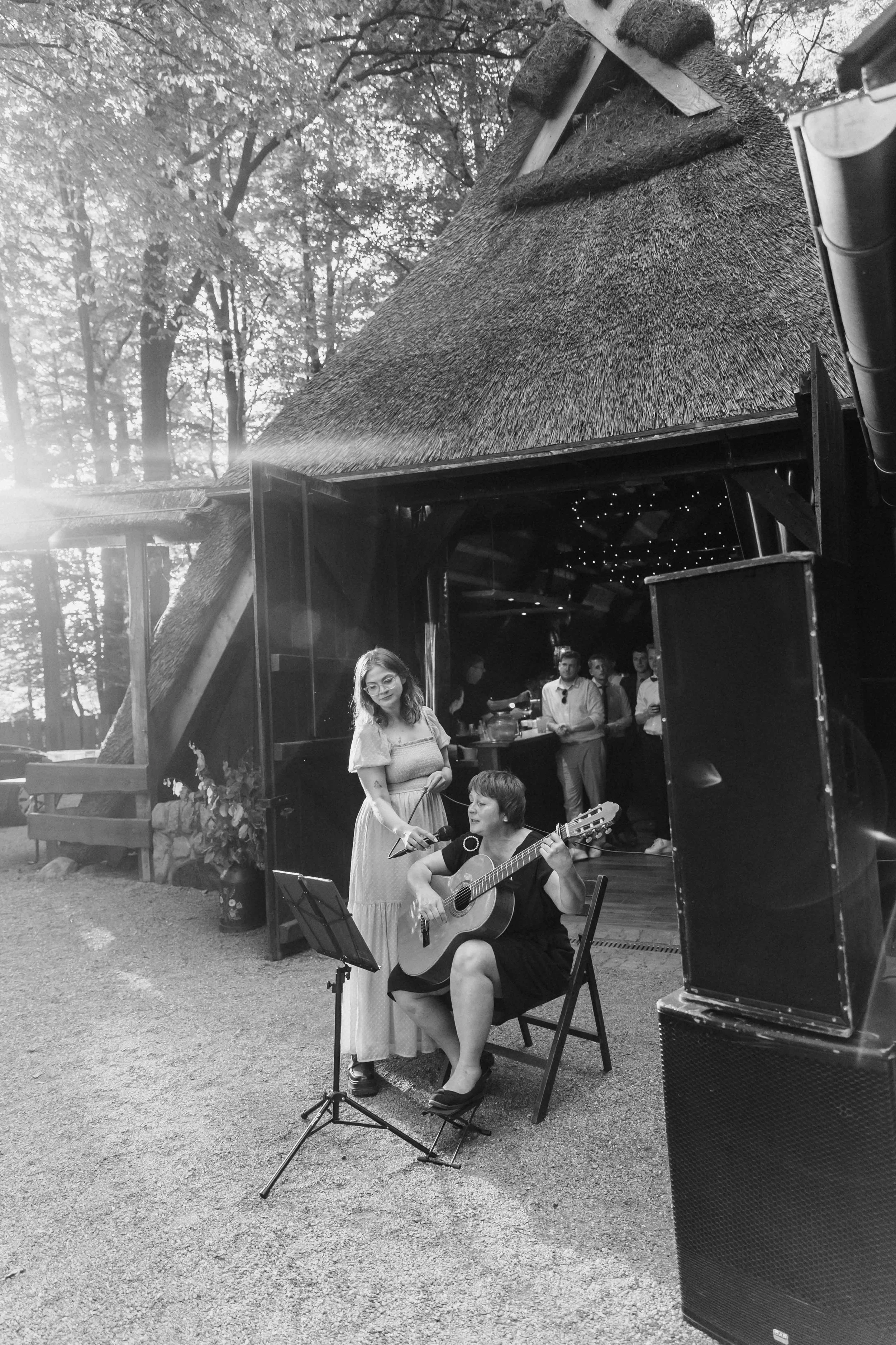 Sängerin und Gitarristin treten bei Sonnenuntergang vor rustikaler Scheune auf