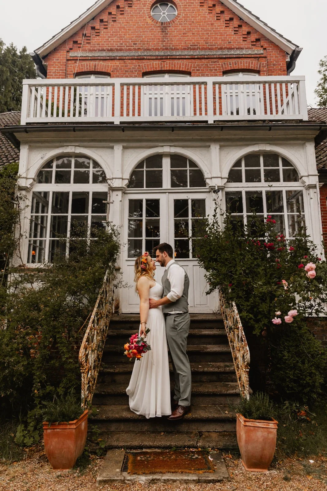 Braut und Bräutigam mit Blumenstrauß vor einer eleganten Villa in Lüneburg