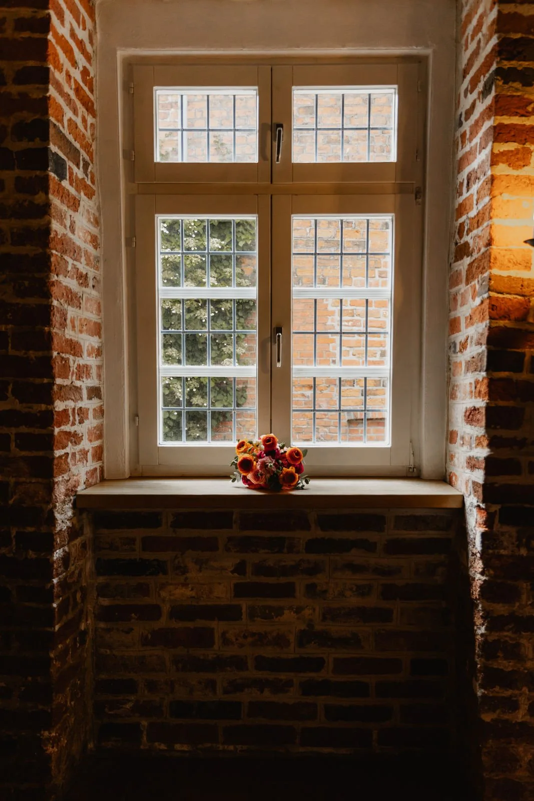 Detailaufnahme eines Brautstraußes auf einer Fensterbank mit Backsteinwand in Lüneburg