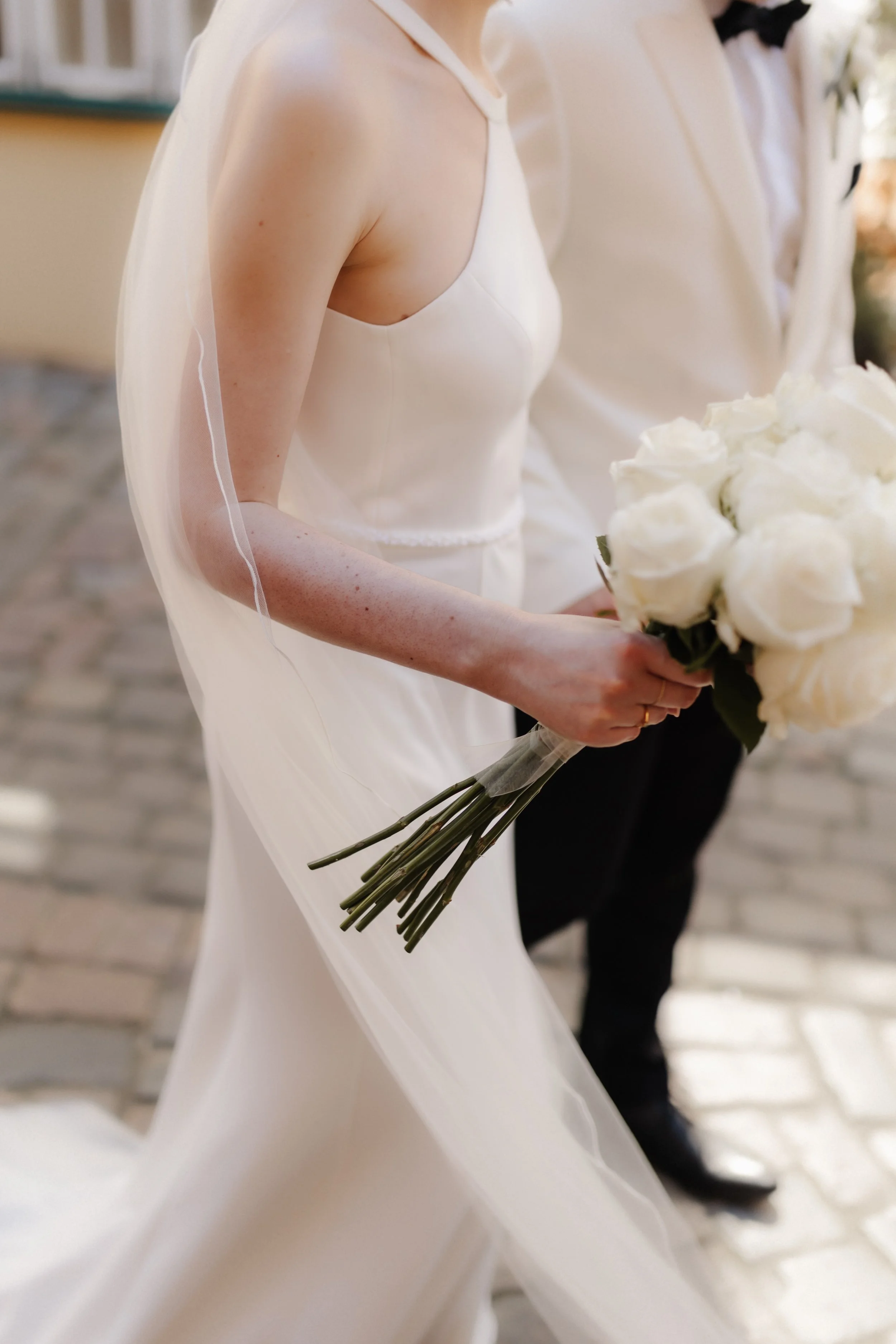 Braut mit schlichtem weißen Brautkleid und Brautstrauß aus weißen Rosen bei einer Hochzeit in Lüneburg.