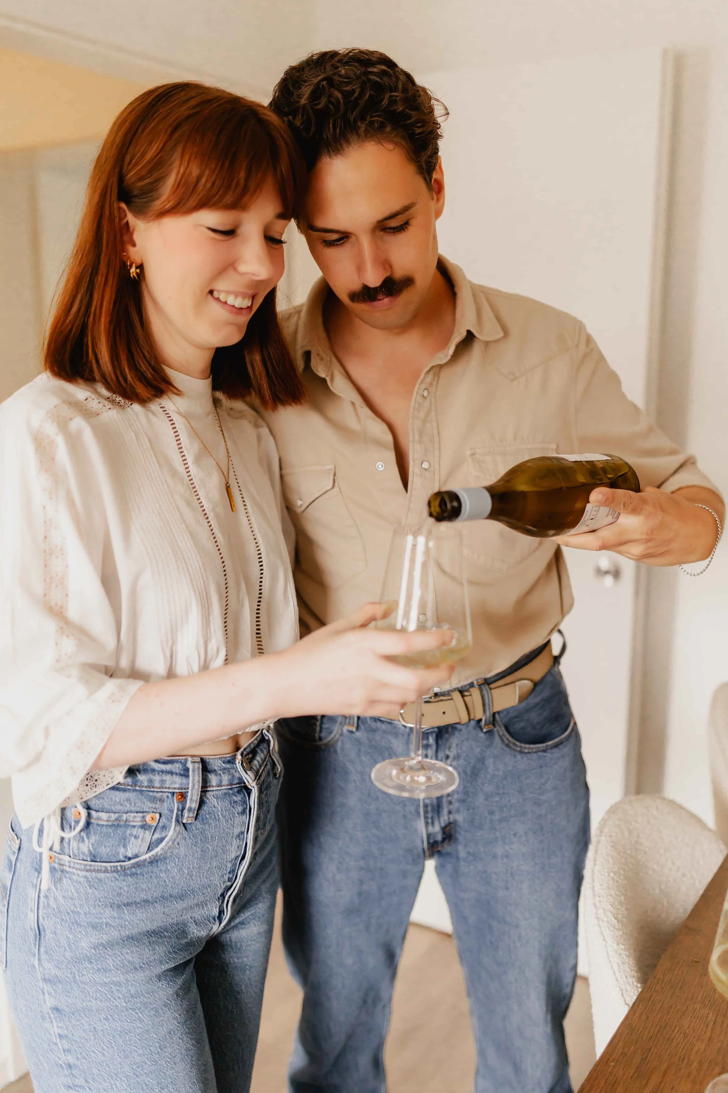 Paar bei einer Homestory in Lüneburg, der Mann schenkt Wein in ein Glas ein, beide lächeln dabei