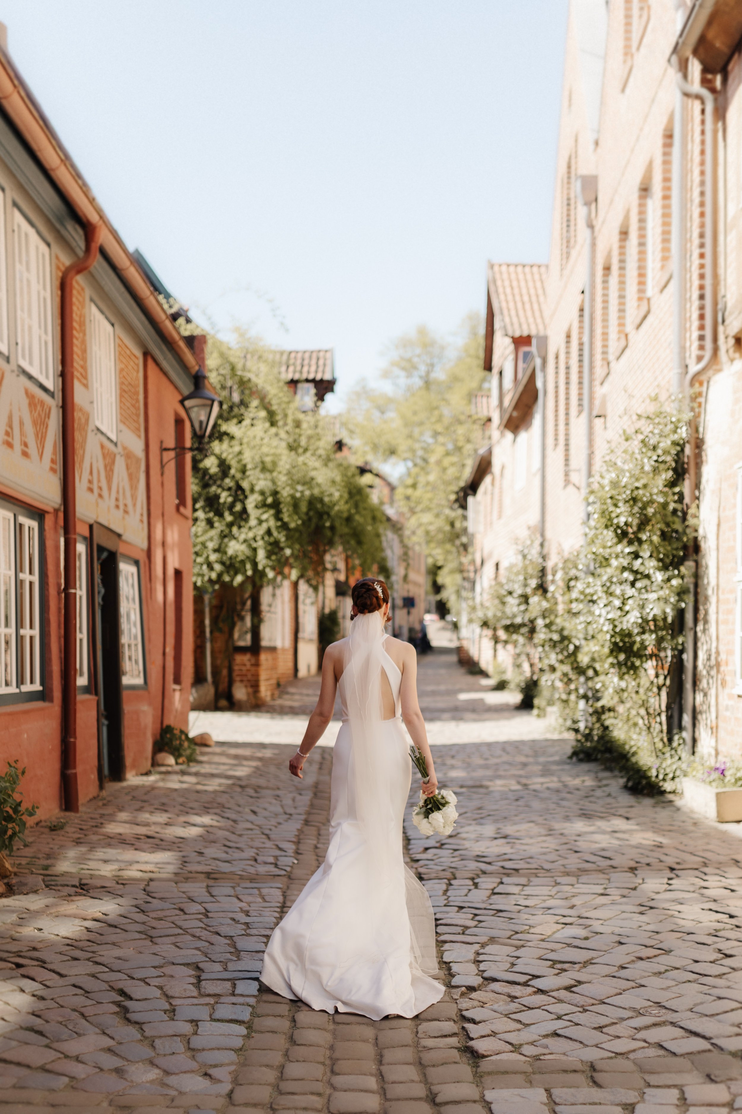 Braut im weißen Brautkleid mit Brautstrauß beim Spaziergang durch die historische Lüneburger Altstadt.