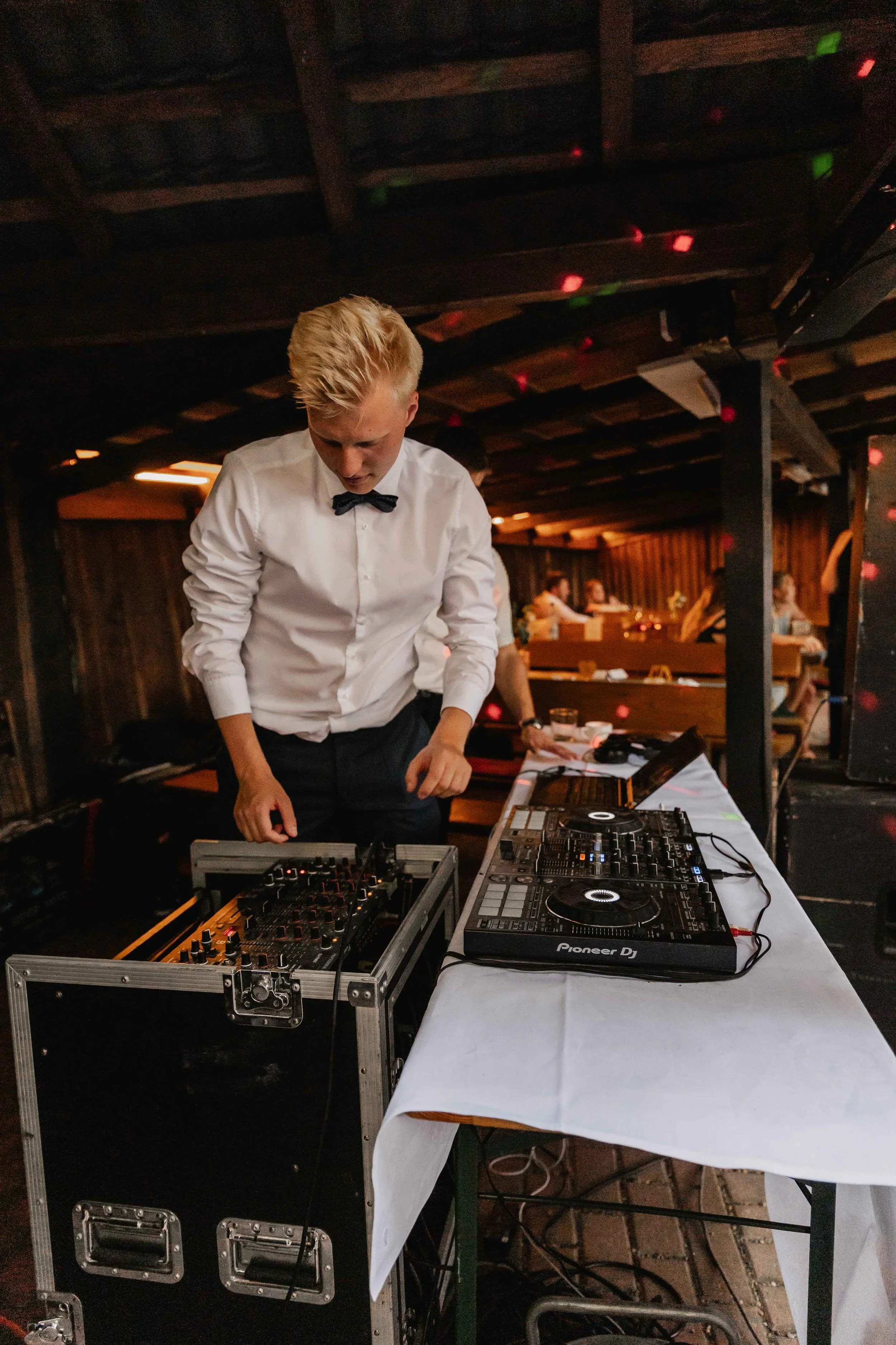 DJ mixt Musik für die Hochzeitsparty unter buntem Licht in der Hütte
