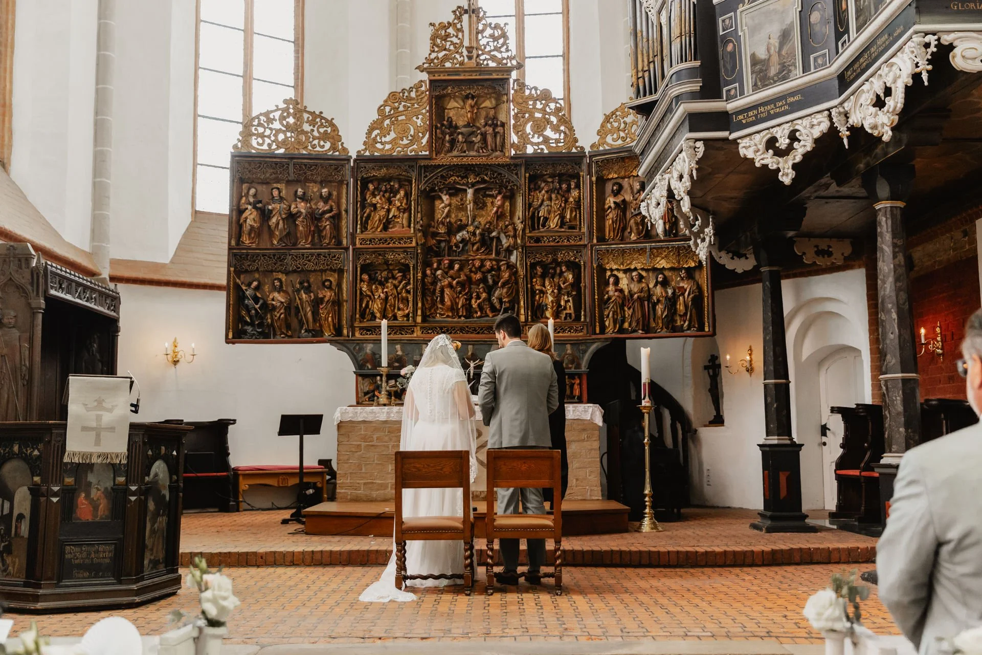 Brautpaar steht während der Trauung am Altar in einer Kirche in Lüneburg
