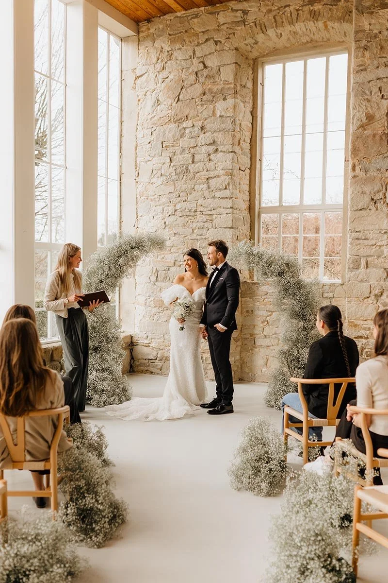 Brautpaar während einer emotionalen freien Trauung in einer hellen, eleganten Hochzeitslocation mit Natursteinwänden