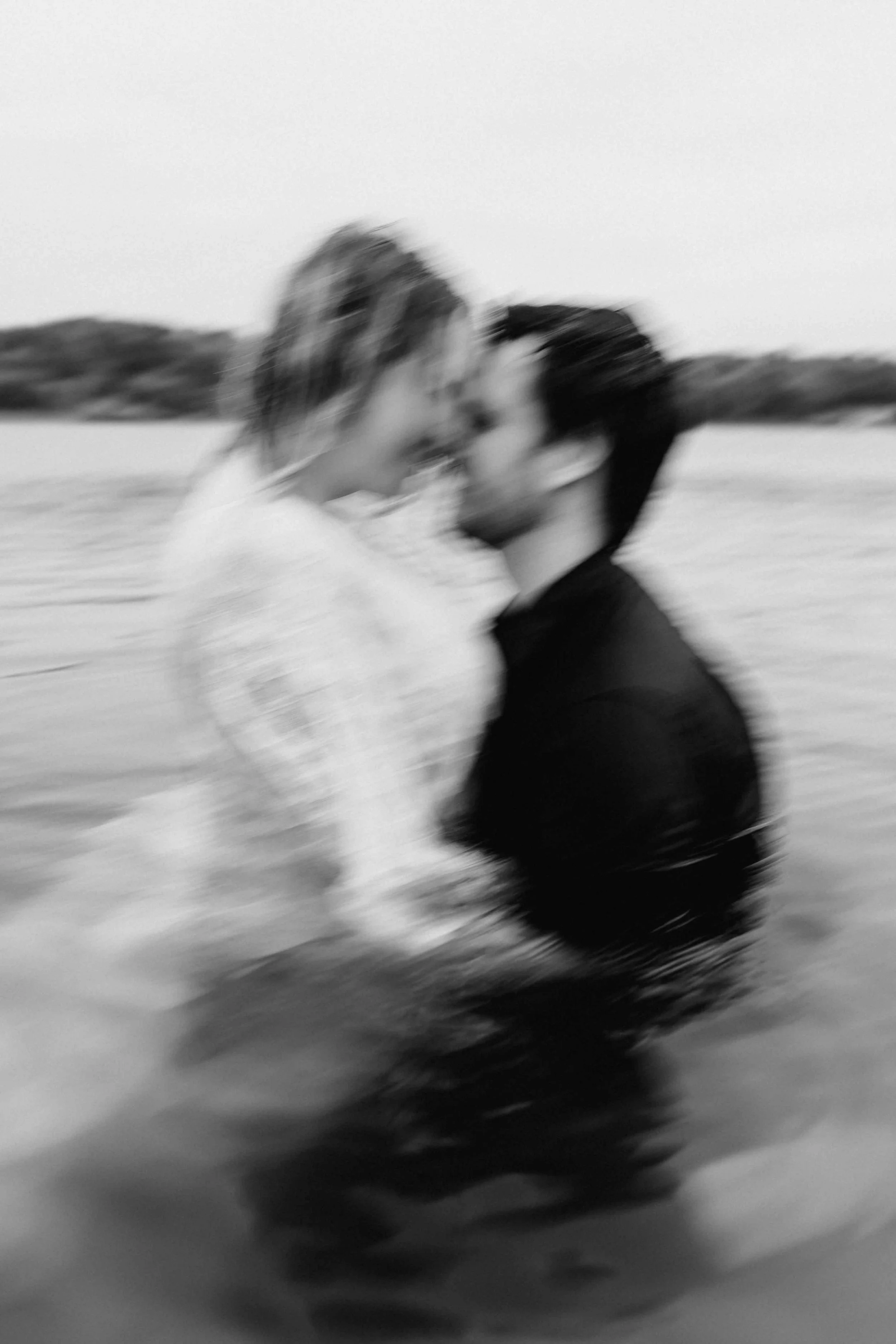 Paar steht eng umschlungen im Wasser, sie lehnt sich zärtlich an ihn