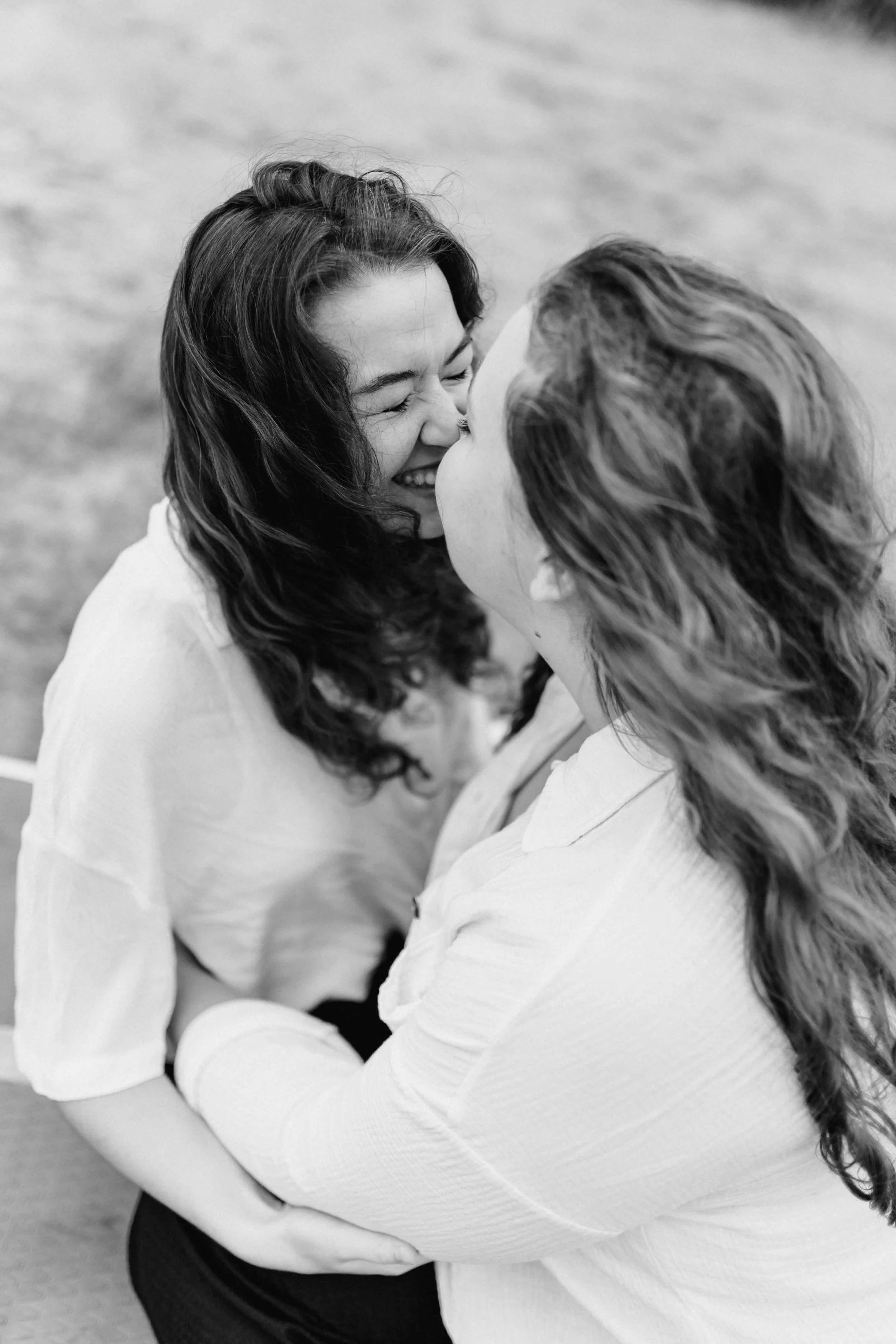 Schwarz-Weiß-Aufnahme von zwei Frauen, die sich lachend umarmen