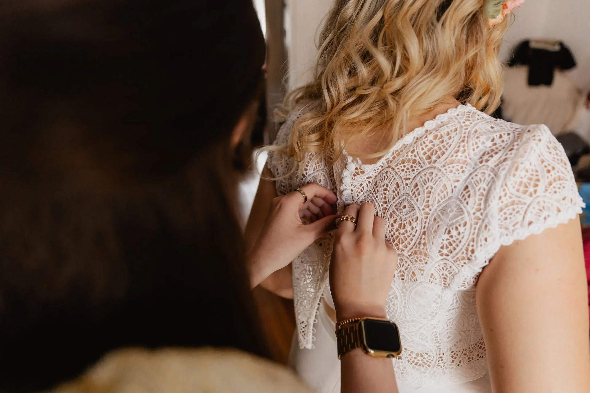Detailaufnahme beim Getting Ready in Lüneburg wie das Spitzen-Brautkleid der Braut im Rücken geschlossen wird