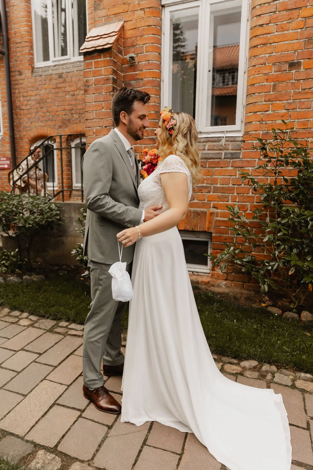 Brautpaar in innigem Moment vor roter Backsteinfassade während der Hochzeit in Lüneburg