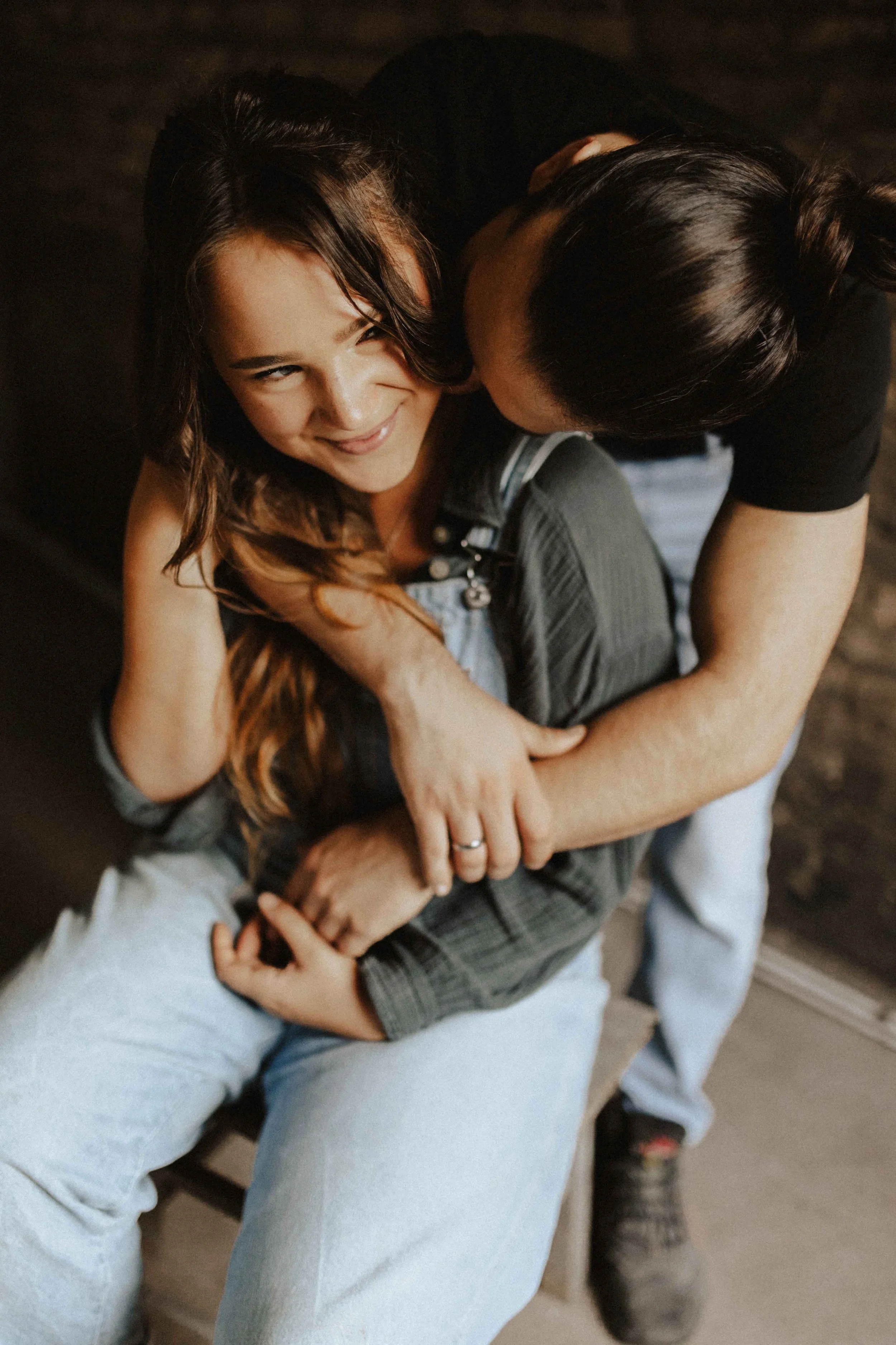 Verliebtes Paarshooting in Lüneburg – Mann umarmt seine Partnerin von hinten und küsst sie sanft am Hals, während sie glücklich lächelt, festgehalten von einer kreativen Paarfotografin.