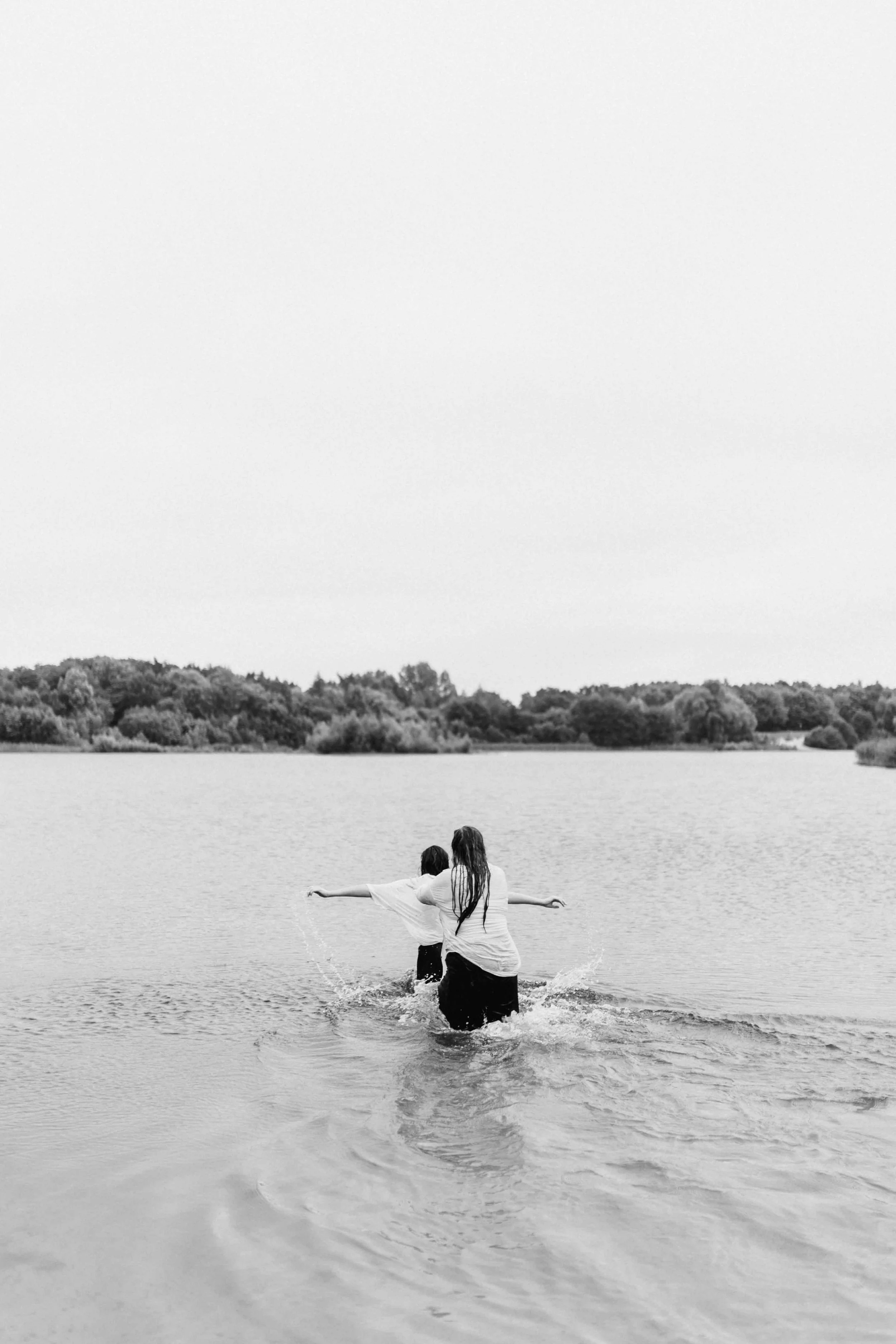 Zwei Frauen umarmen sich im Wasser, schwarz-weiß Fotografie am See