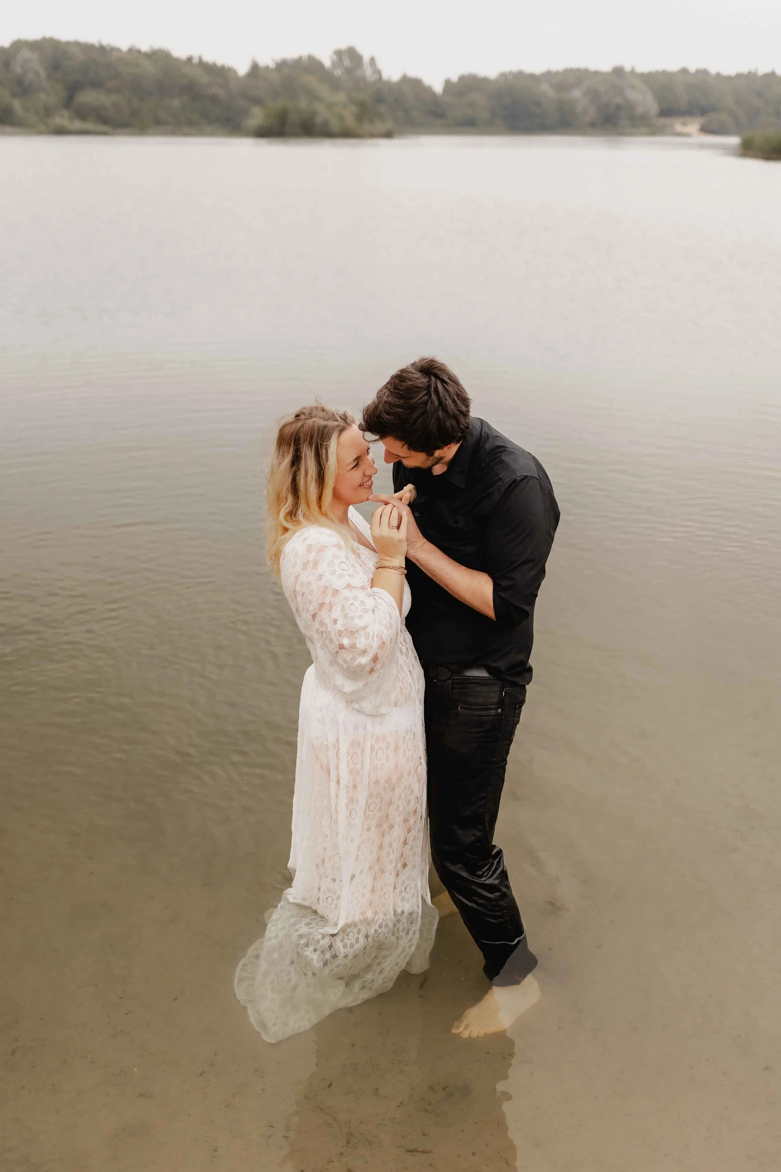 Paar steht barfuß im Wasser und schaut sich verliebt in die Augen