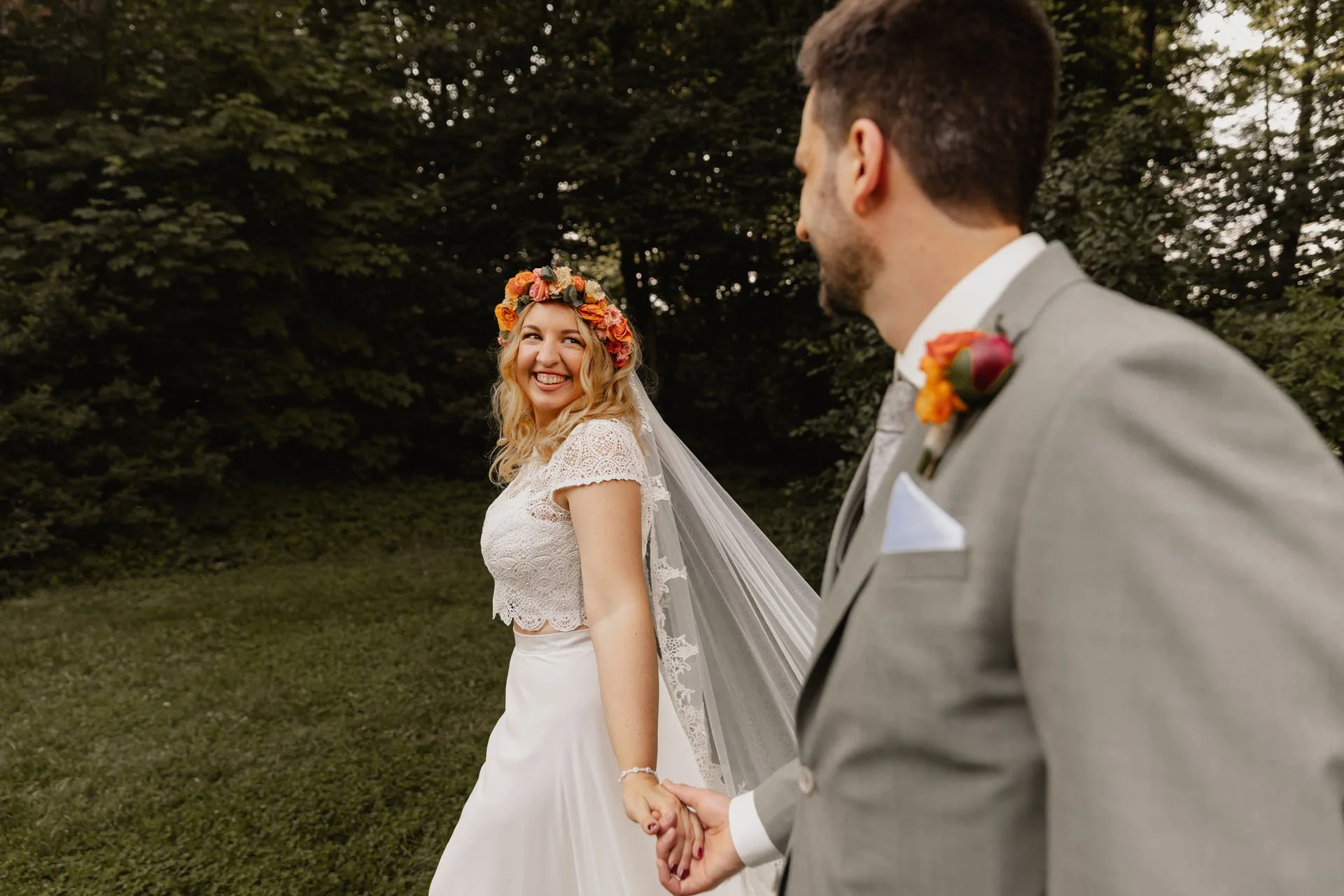 Braut und Bräutigam gehen Hand in Hand durch die Natur bei ihrer Hochzeit in Lüneburg
