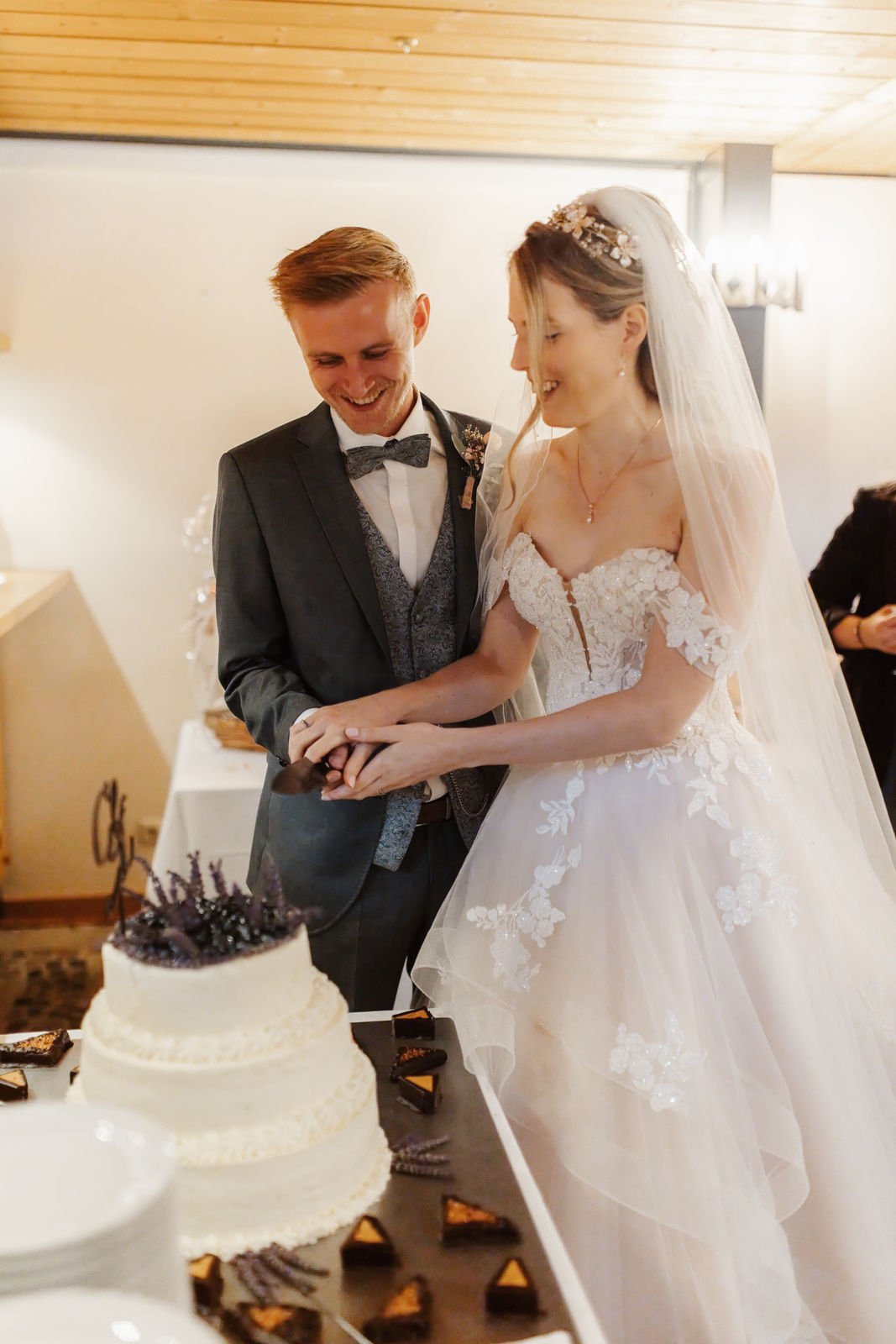 Brautpaar schneidet gemeinsam lachend die Hochzeitstorte im Heide Hotel Reinstorf bei Lüneburg an – ein natürlicher Moment der Hochzeitsreportage.