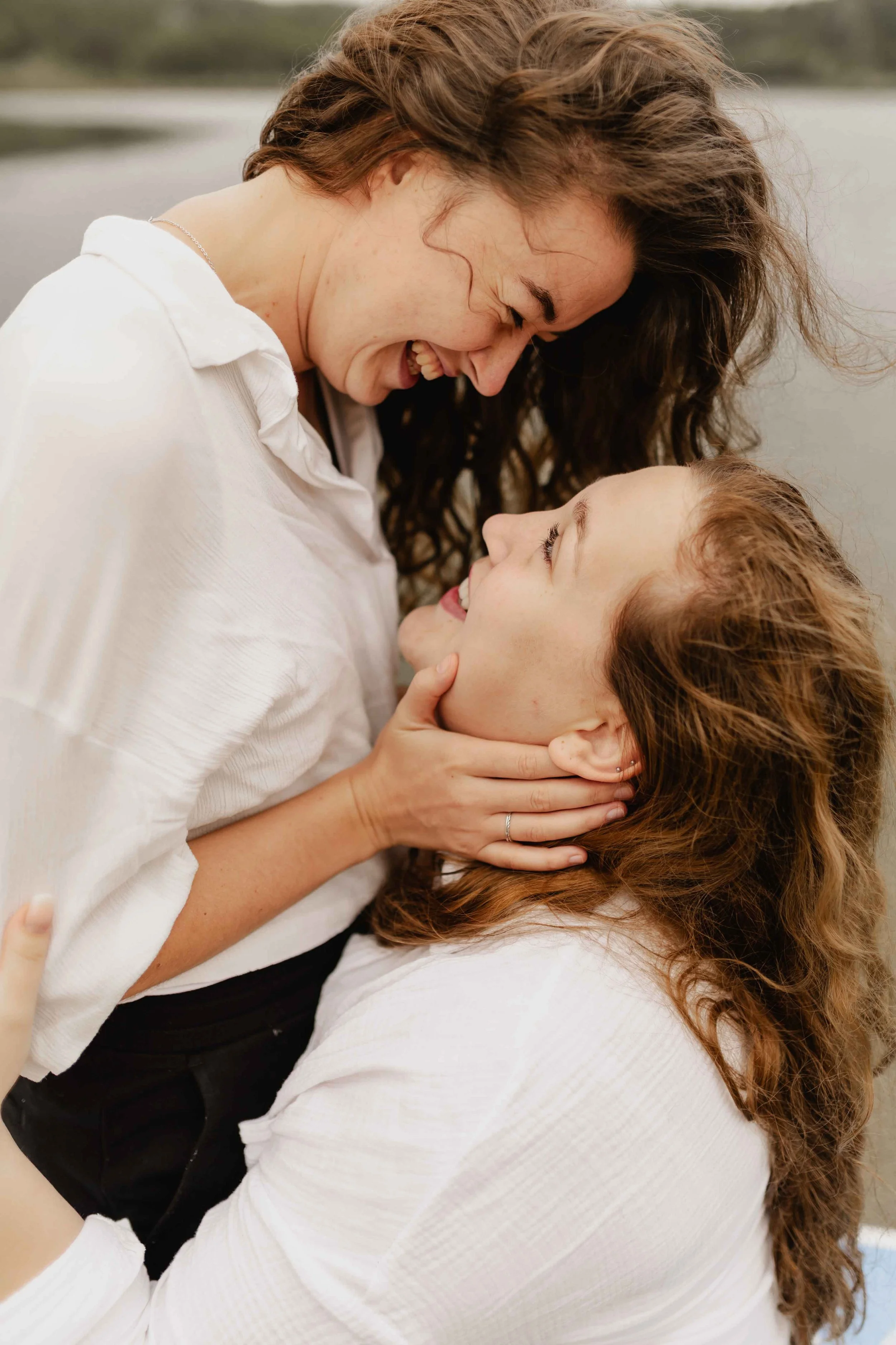 Zwei Frauen halten sich innig und schauen sich verliebt am See in die Augen