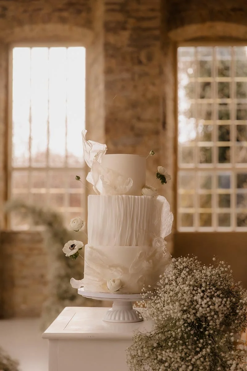Elegante dreistöckige Hochzeitstorte mit weißen Blumen und Schleierkraut – stilvolle Hochzeitsdetails einer natürlichen Hochzeitsreportage in Lüneburg