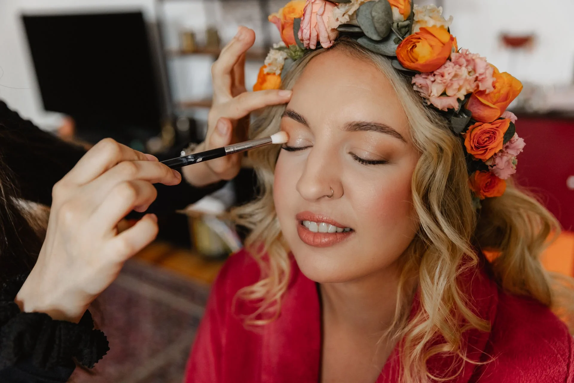 Nahaufnahme beim Getting Ready der Braut in Lüneburg mit Blumenkranz während das Augen-Make-up aufgetragen wird